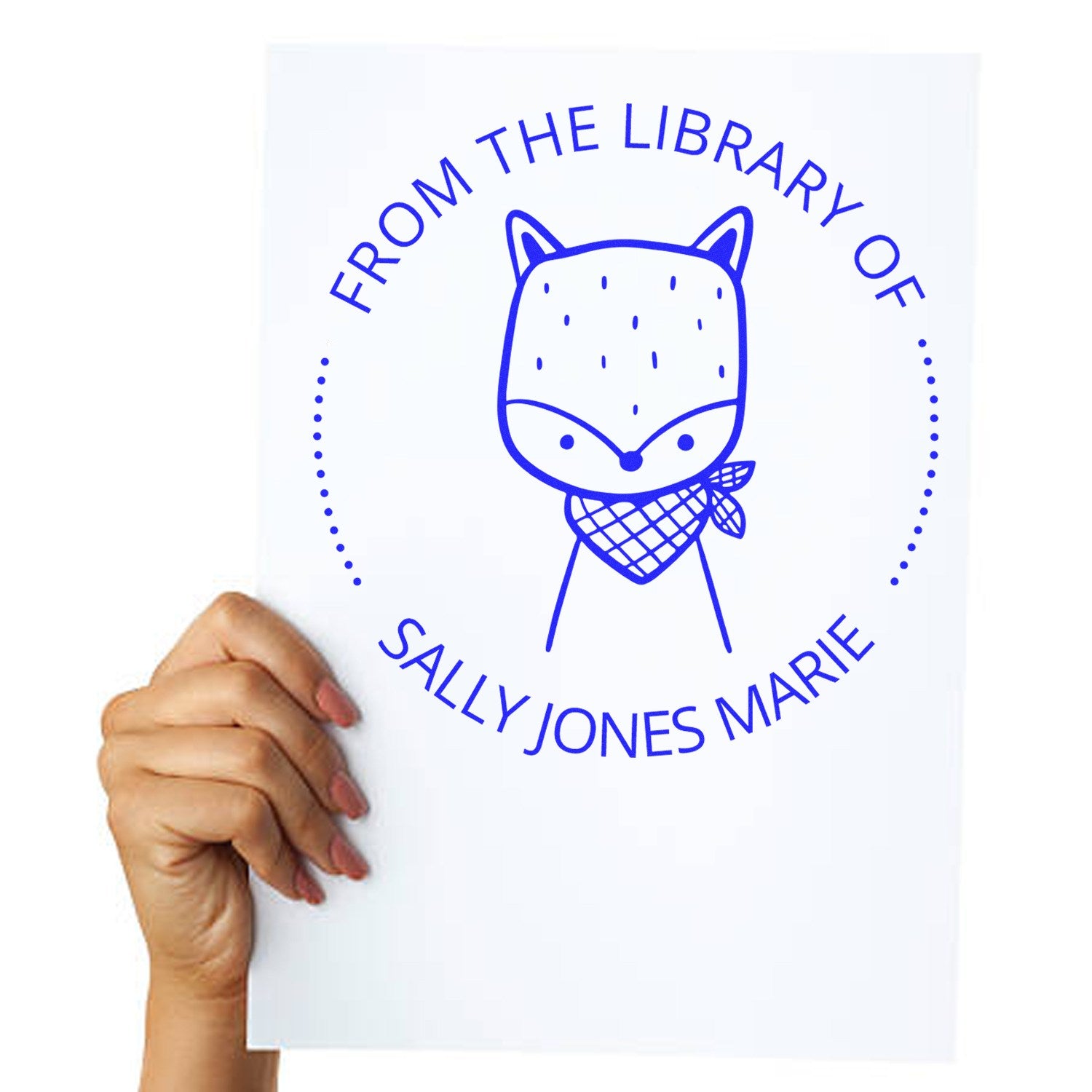 A hand holds a paper stamped with a blue cartoon animal wearing a bandana, encircled by the text "From The Library Of Sally Jones Marie." The Slim Pre-Inked SnickerSnack Cartoon Animal Custom stamp is a Personalized Home Stamp from the Private Library collection.
