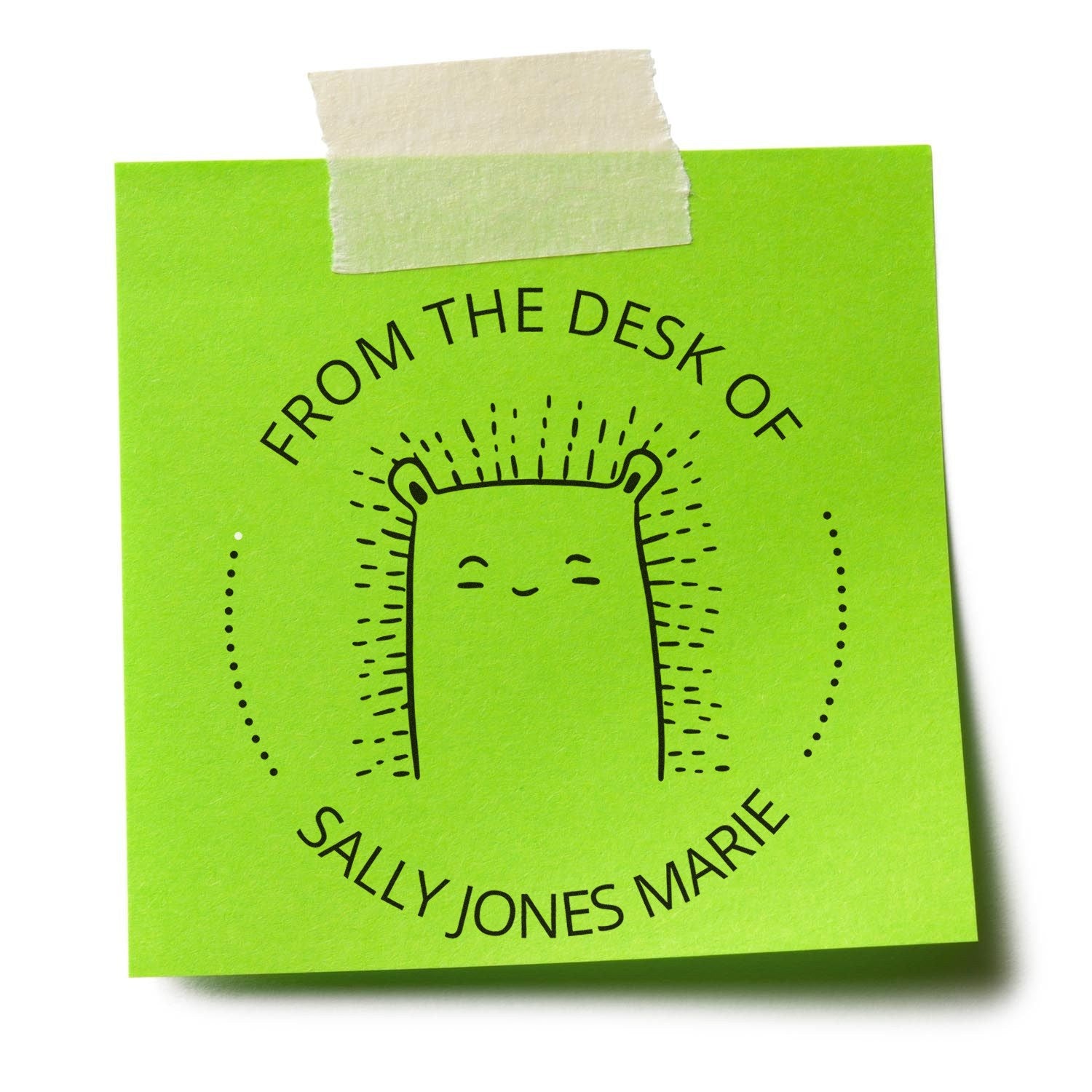 A green sticky note with a FizzleFluff cartoon animal design, stamped with From the Desk of Sally Jones Marie. The self-inking stamp is used for personalizable book marking and mailing, showcasing its versatility.