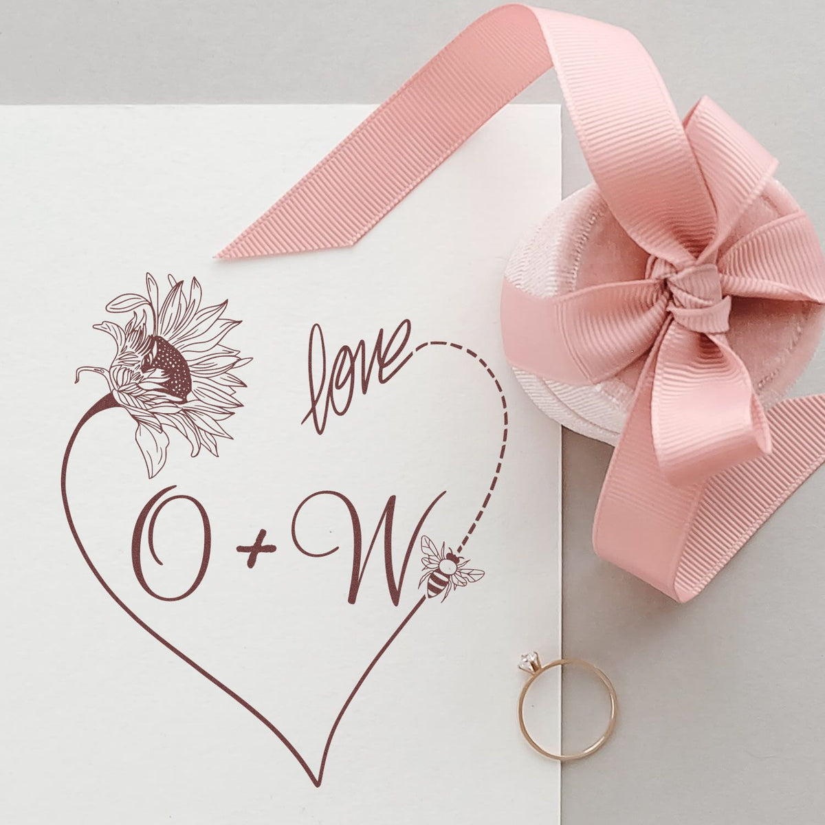 Custom brown wedding stamp seal on white card with sunflower heart monogram, pink ribbon bow, and gold ring