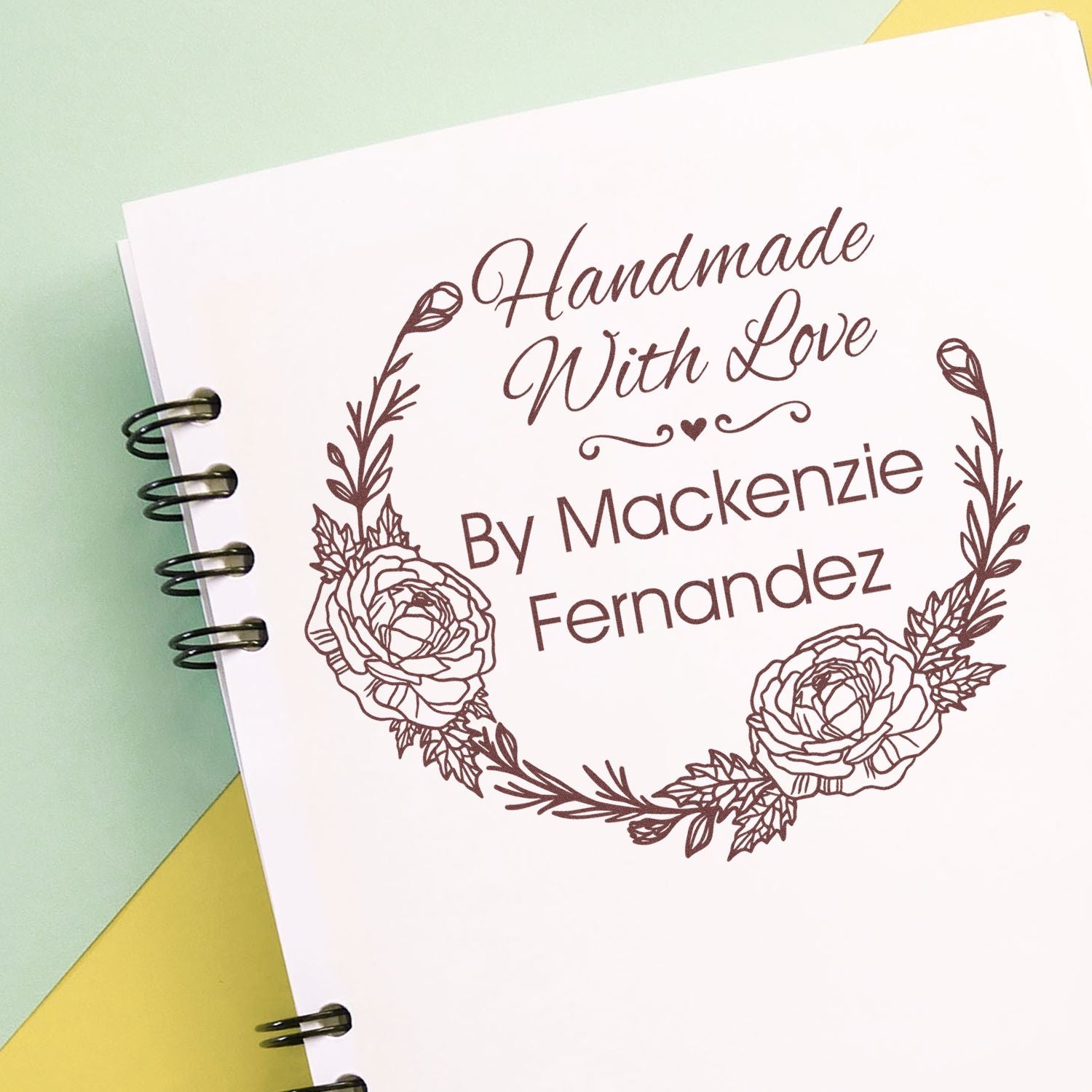 Brown custom stamp seal on white card, reading Handmade With Love by Mackenzie Fernandez, framed by floral wreath.