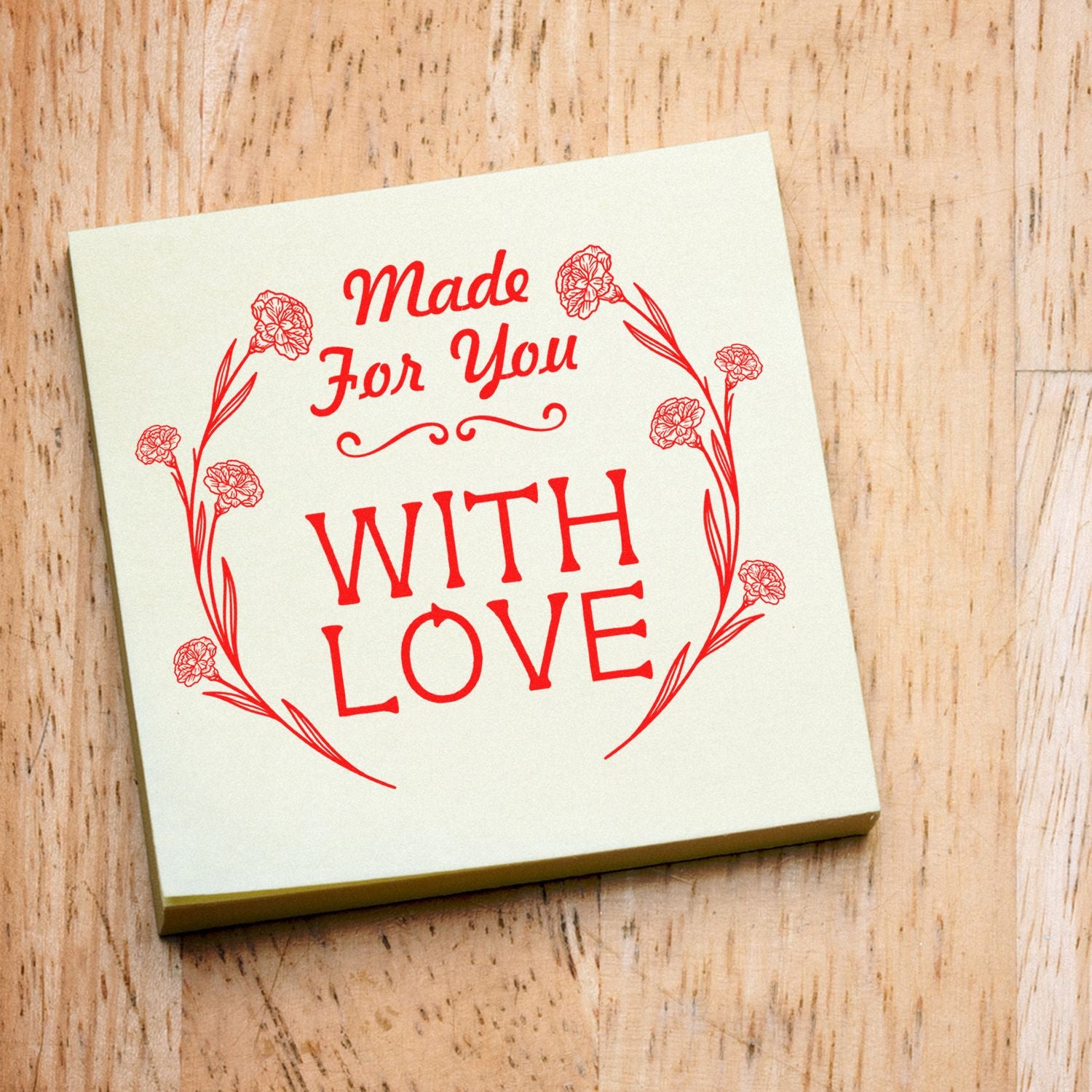 Cream stamp pad with red Made For You With Love floral wreath design on a light wood background.