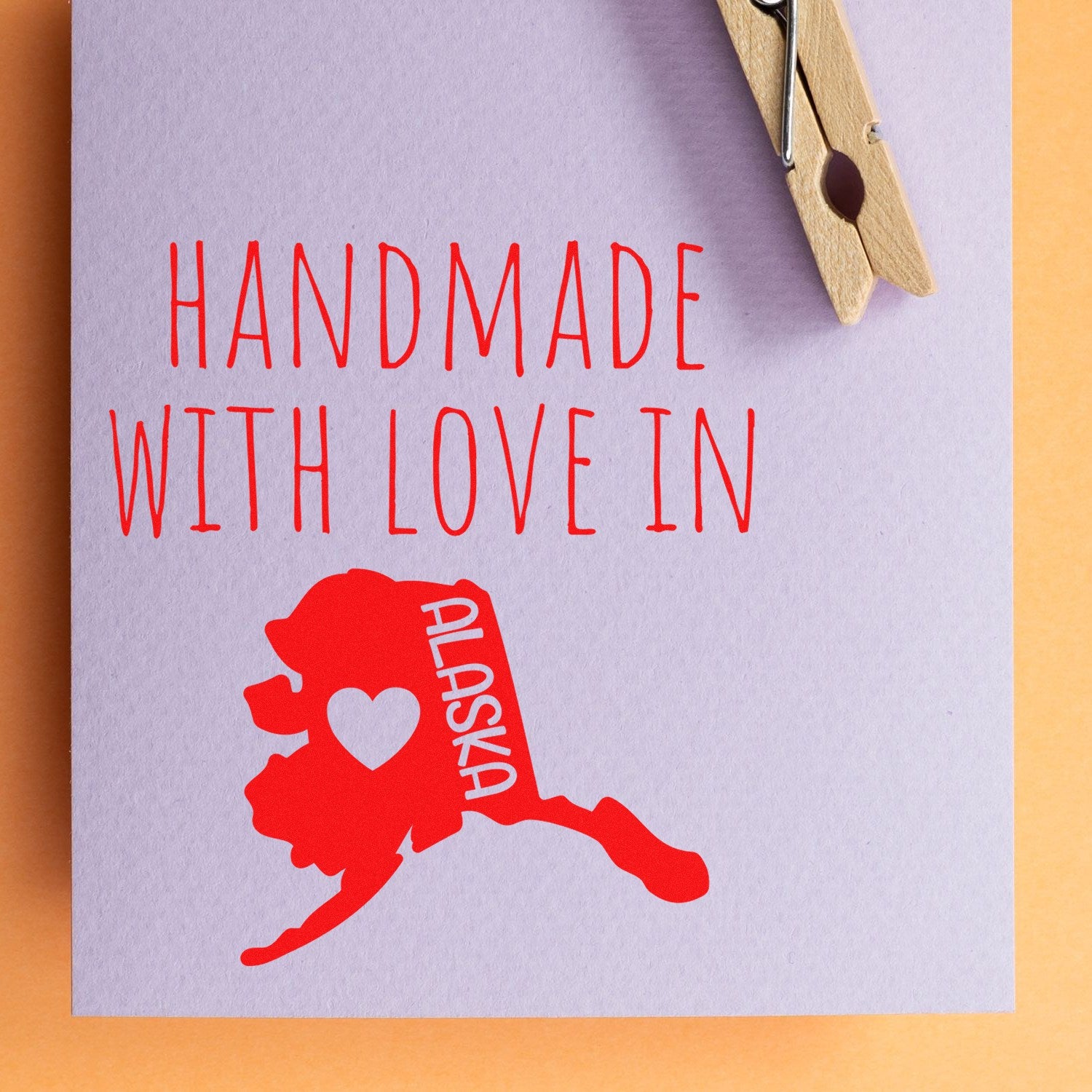 Wood Handle Alaska Handmade with Love Rubber Stamp on paper, featuring a red Alaska map with a heart, showcasing craftsmanship and love. Perfect for personalized projects and gifts.