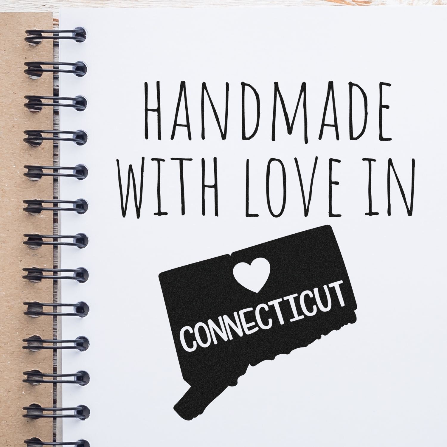 Self-Inking Connecticut Handmade with Love Stamp on a notebook, featuring a heart and state outline design. Perfect for crafts and gifts.