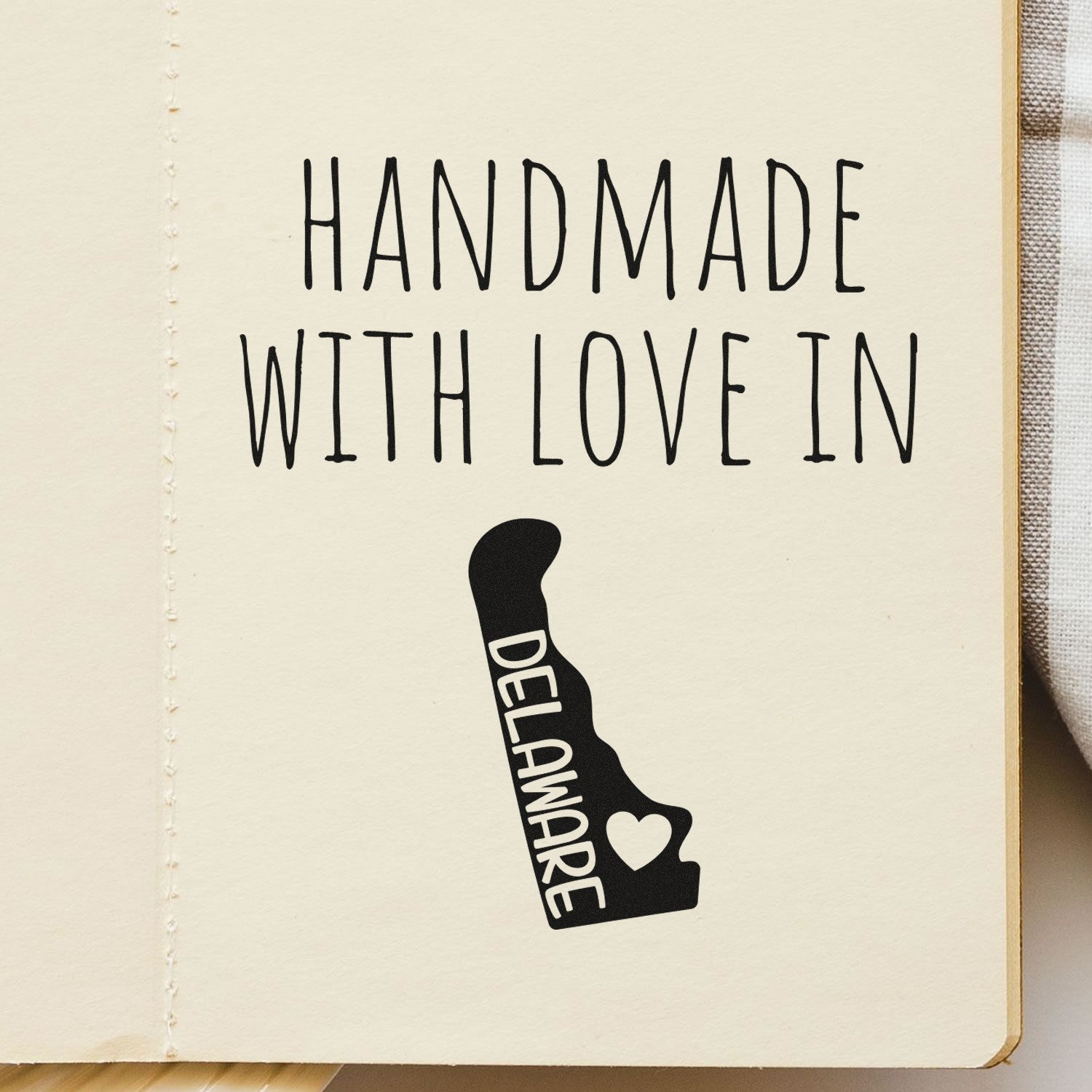 Handmade with Love in Delaware Slim Pre-Inked Stamp on paper, featuring a heart and state outline design. Perfect for crafts and personalizing stationery.