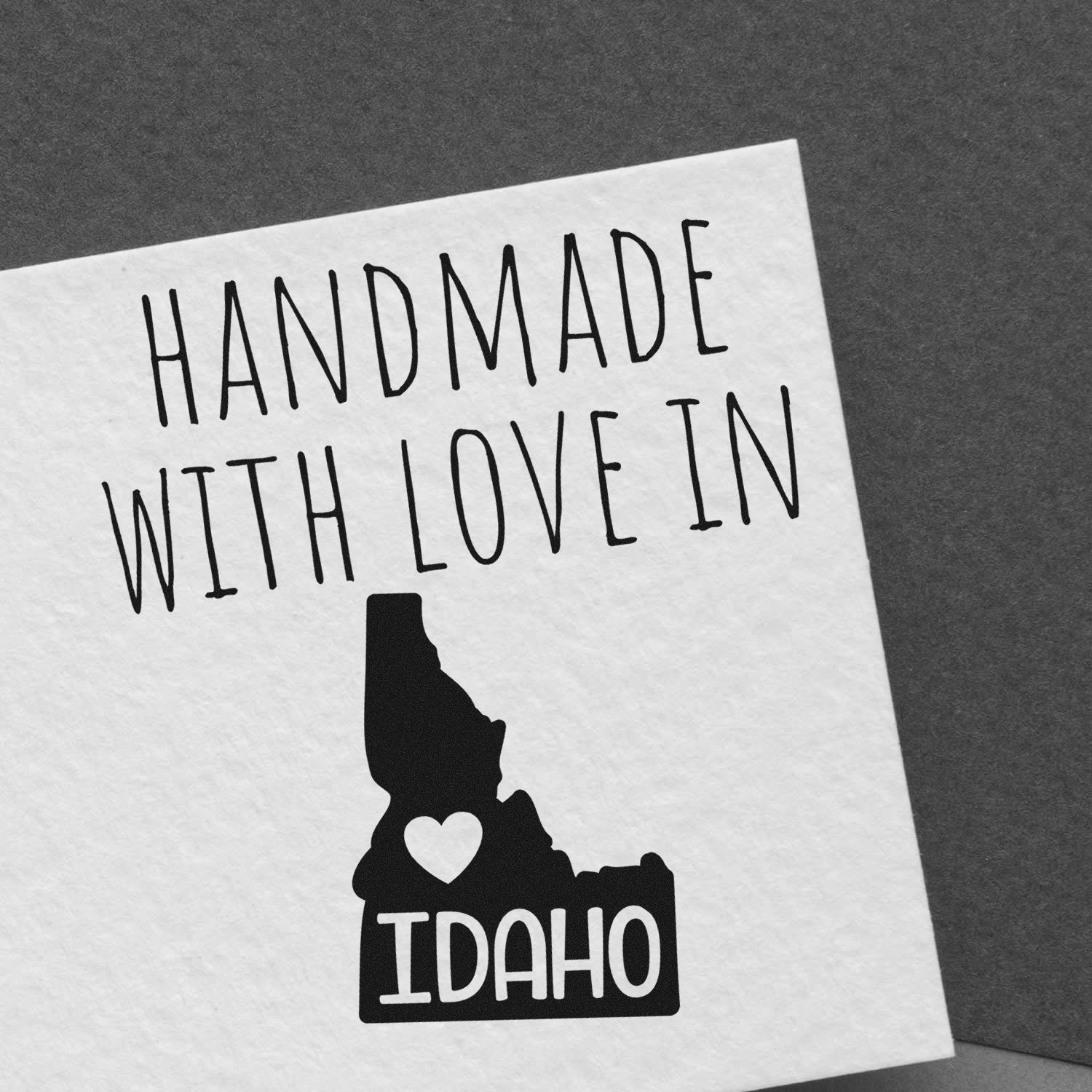 Wood Handle Idaho Handmade with Love Rubber Stamp on white paper, featuring a heart and the word Idaho in bold, showcasing craftsmanship and state pride.