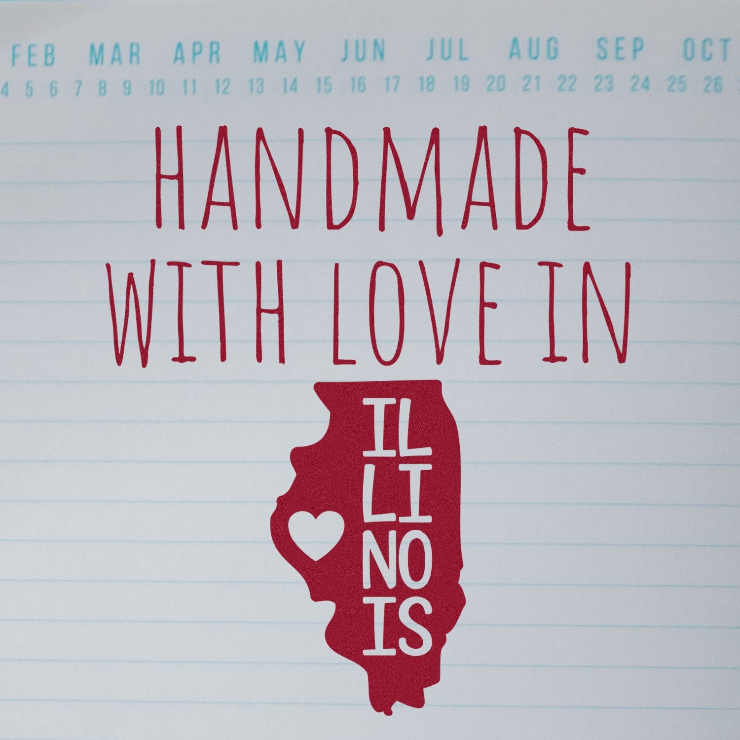 Self-Inking Illinois Handmade with Love Stamp featuring a red Illinois state outline with a heart, set against a lined background with months at the top. Perfect for crafts and gifts.