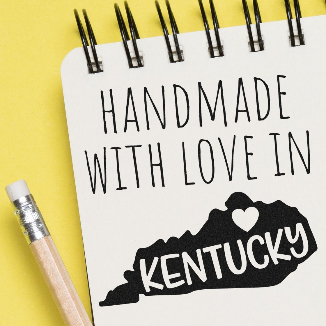 Self-Inking Kentucky Handmade with Love Stamp on a notepad with a pencil, featuring a heart and Kentucky state outline, perfect for crafts and gifts.