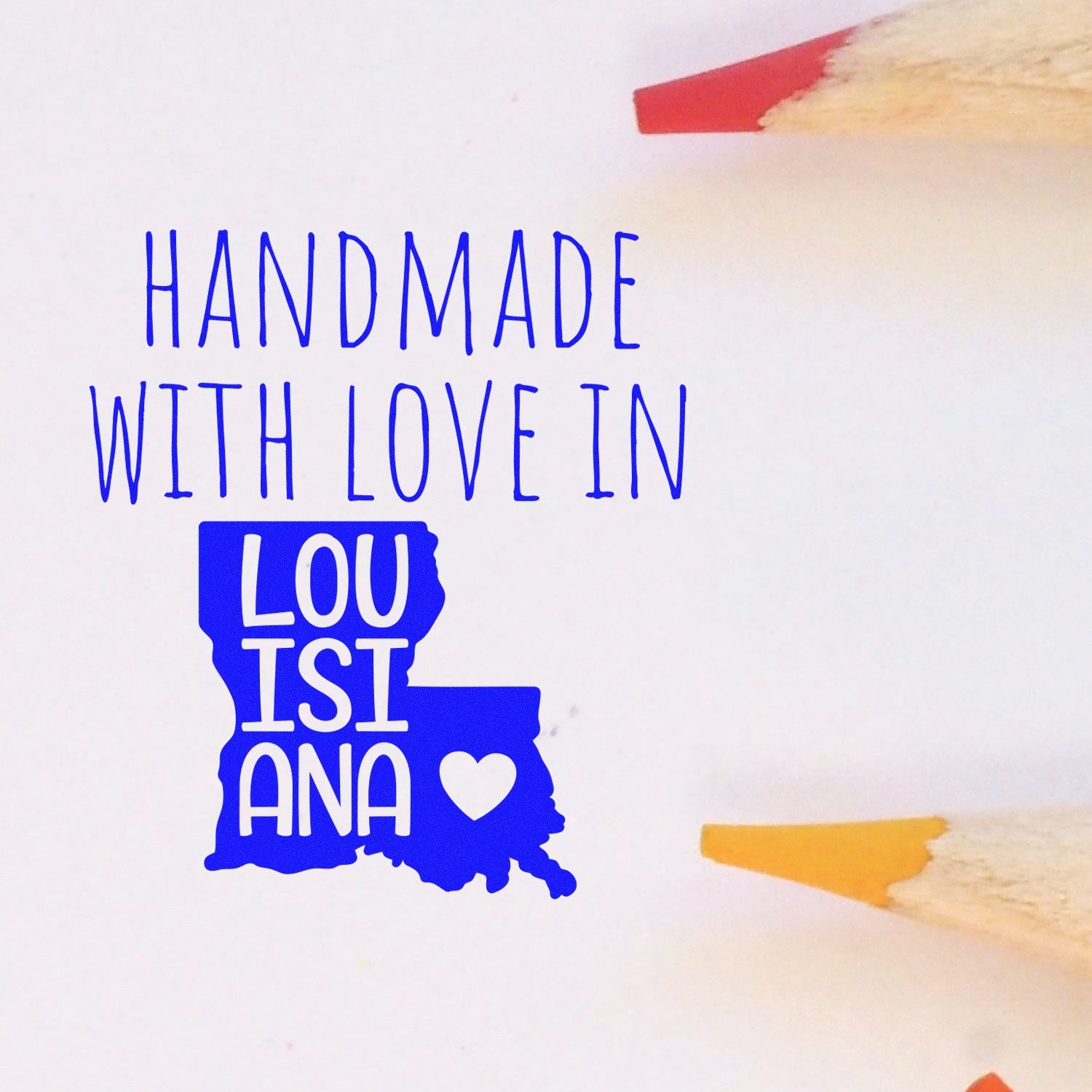 Handmade with Love in Louisiana Slim Pre-Inked Stamp featuring a blue Louisiana map design with a heart, surrounded by colored pencils on a white background.