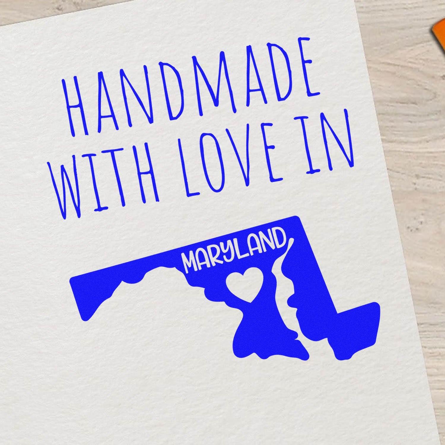 Wood Handle Maryland Handmade with Love Rubber Stamp on paper, featuring a blue Maryland state outline with Handmade with Love text. Perfect for crafts and personalized projects.