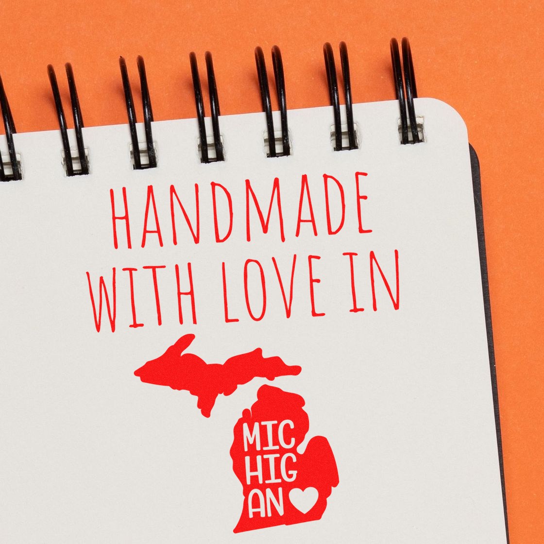 Self-Inking Michigan Handmade with Love Stamp featuring a red Michigan map and heart design on a spiral notebook, perfect for crafts and gifts.