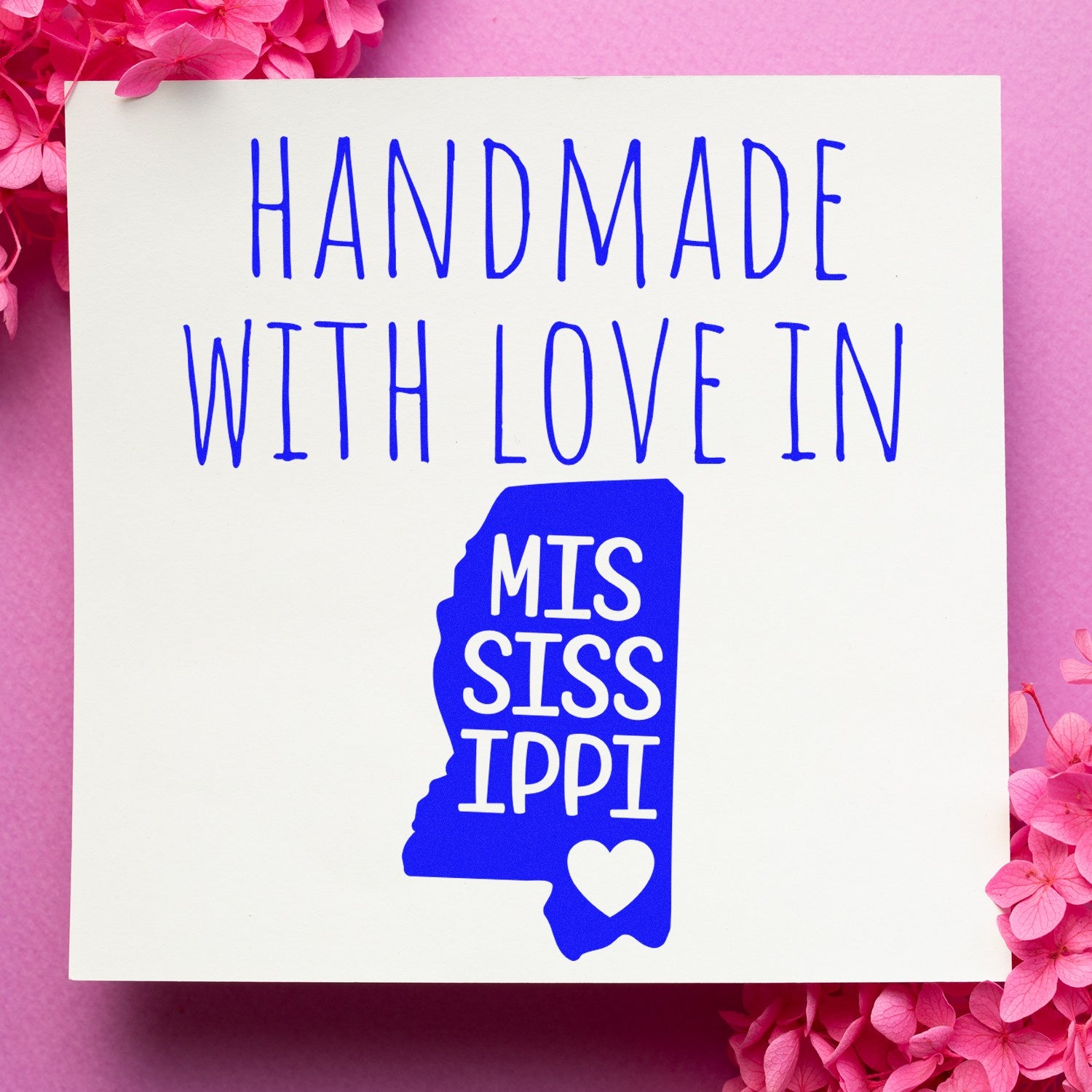 Handmade with Love in Mississippi Slim Pre-Inked Stamp on pink background with floral accents, featuring blue text and state outline design.