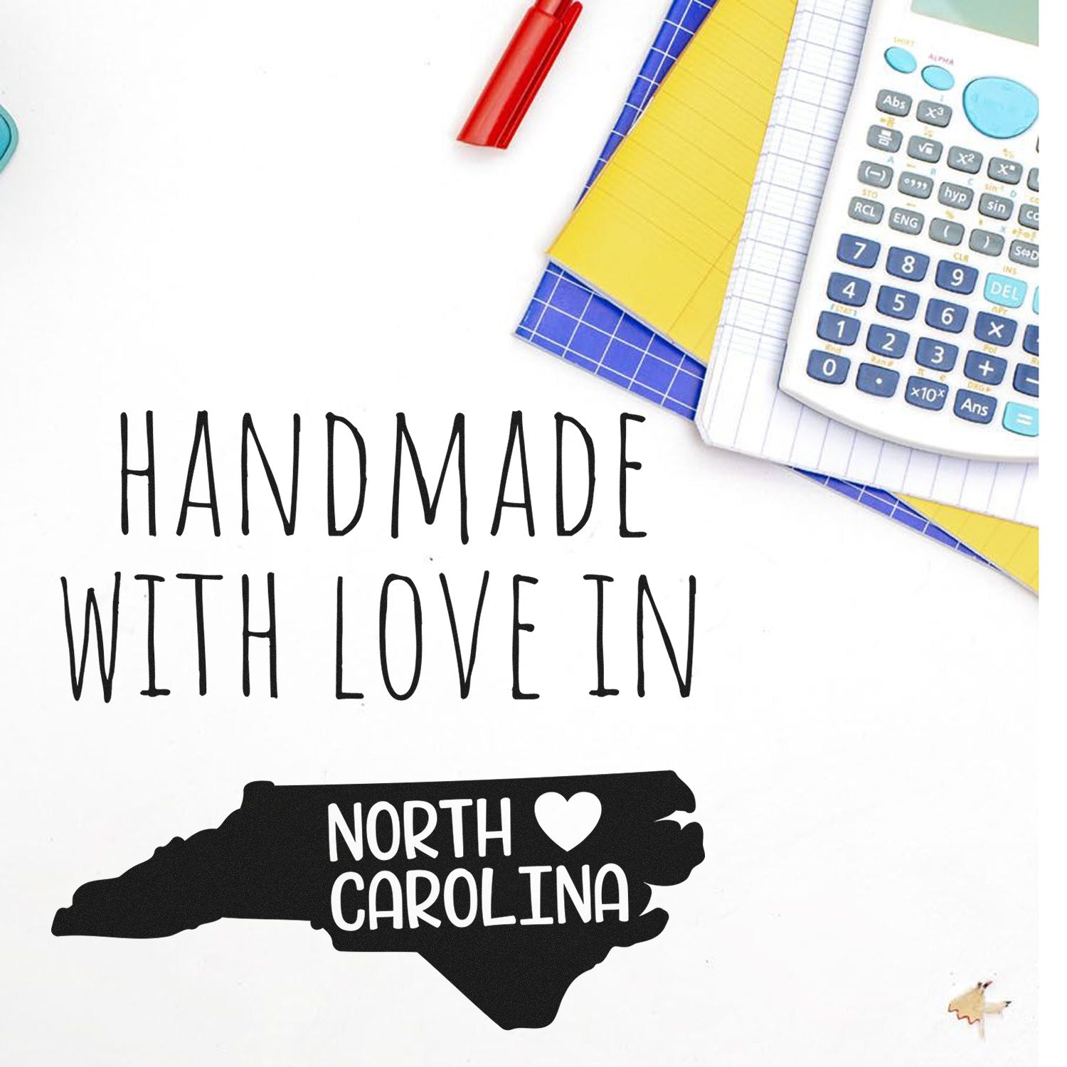 PSI Pre-Inked Handmade with Love in North Carolina stamp, featuring a map outline with a heart, placed on a desk with stationery items.