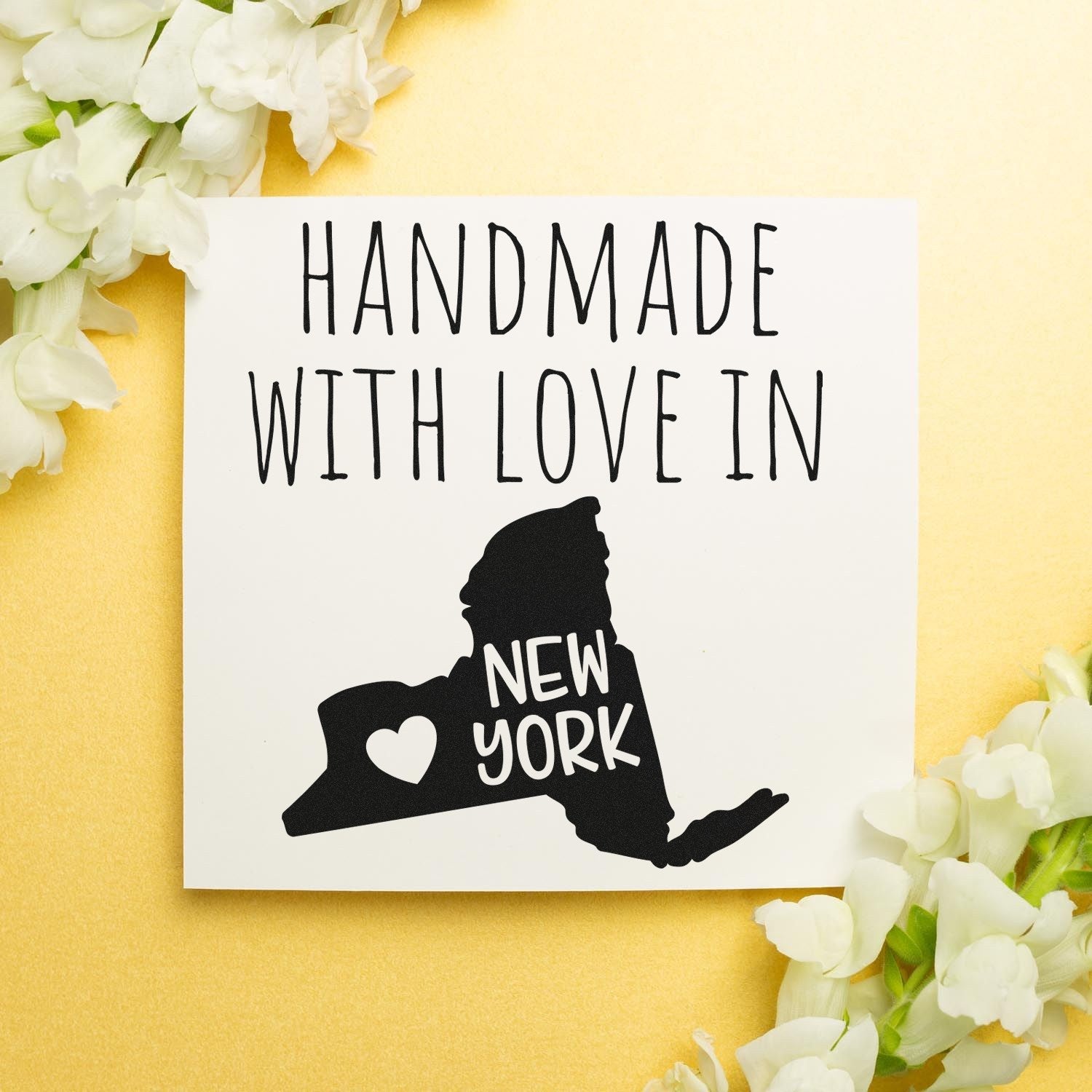 Self-Inking New York Handmade with Love Stamp featuring a black silhouette of New York state with a heart, surrounded by white flowers on a gold background.