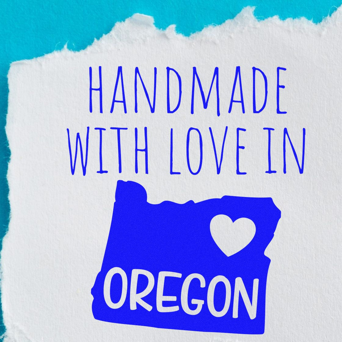 PSI Pre-Inked Handmade with Love in Oregon stamp on torn paper, featuring a blue map of Oregon with a heart, emphasizing its handcrafted origin.