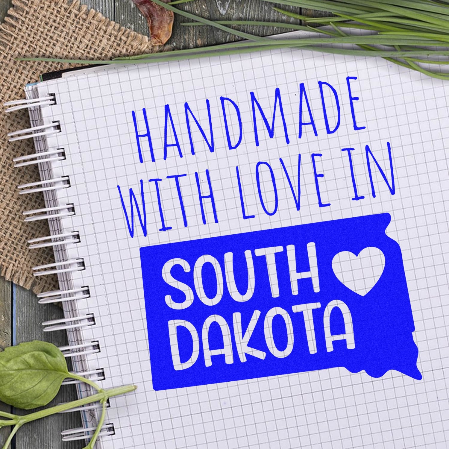 Self-Inking South Dakota Handmade with Love Stamp on a notebook, featuring a blue map outline and heart design, perfect for adding a personal touch to crafts and gifts.