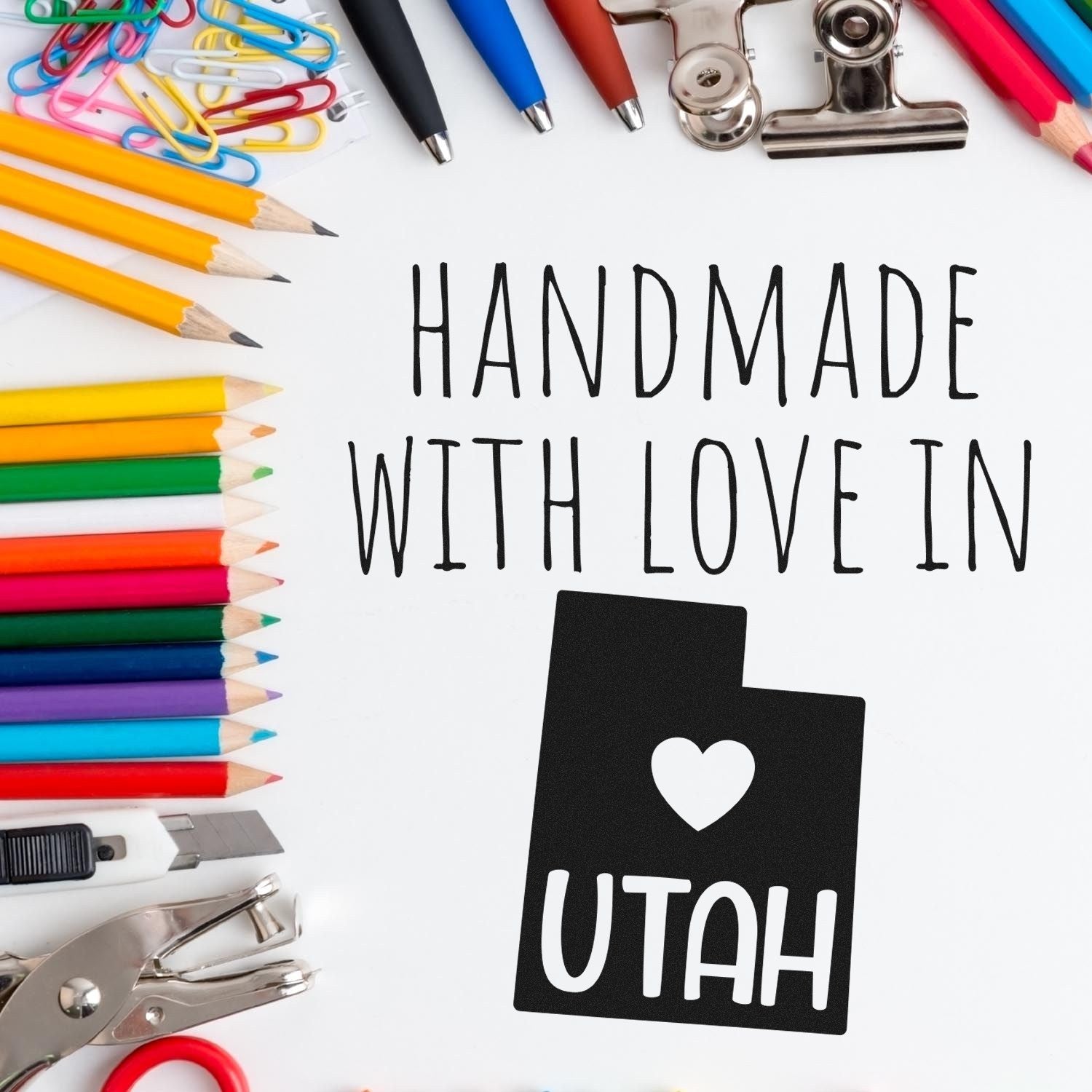 Wood Handle Utah Handmade with Love Rubber Stamp on a desk surrounded by colorful pencils, paperclips, and scissors, showcasing its unique design and craftsmanship.