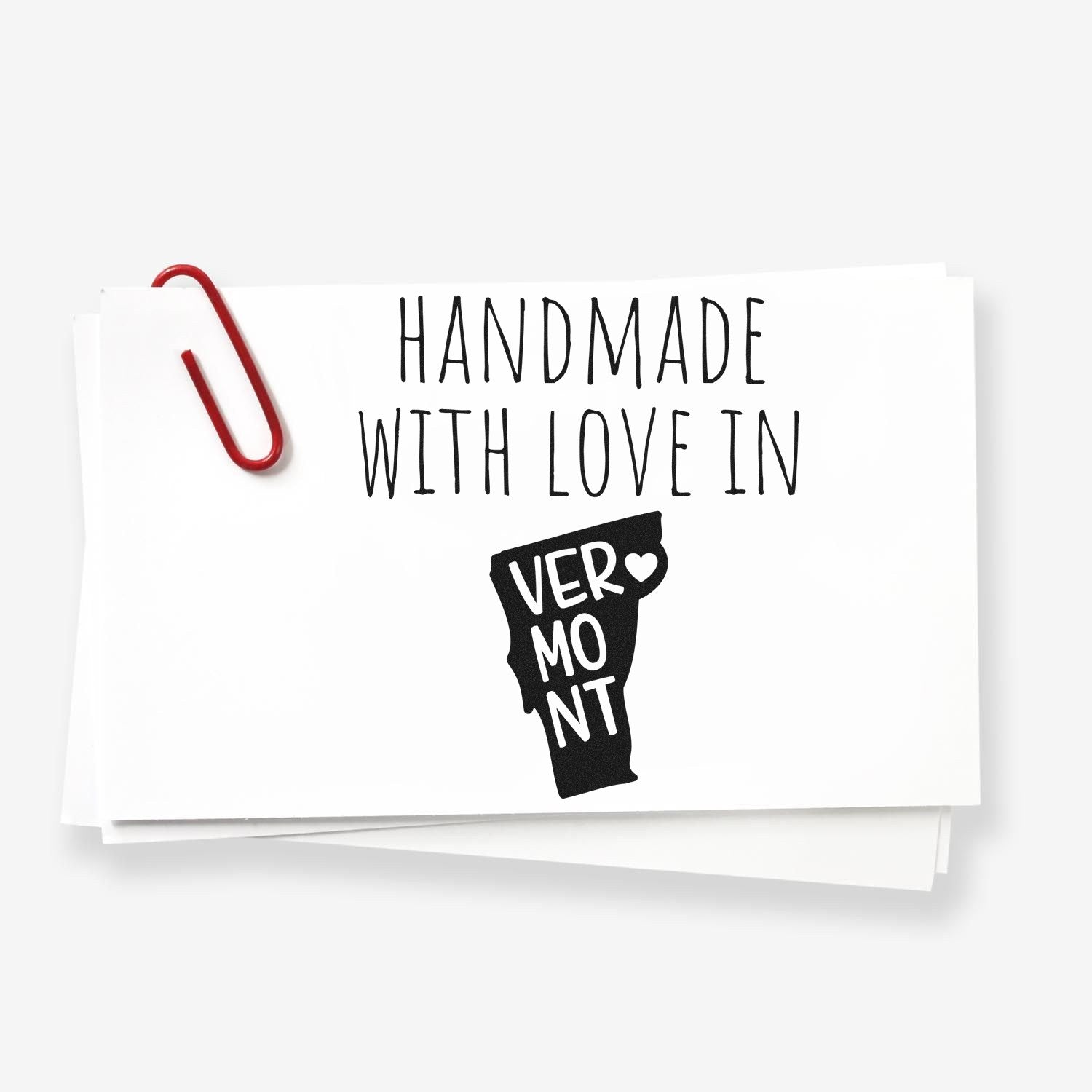 Handmade with Love in Vermont Slim Pre-Inked Stamp featuring a Vermont state outline with a heart, displayed on white cards with a red paperclip.