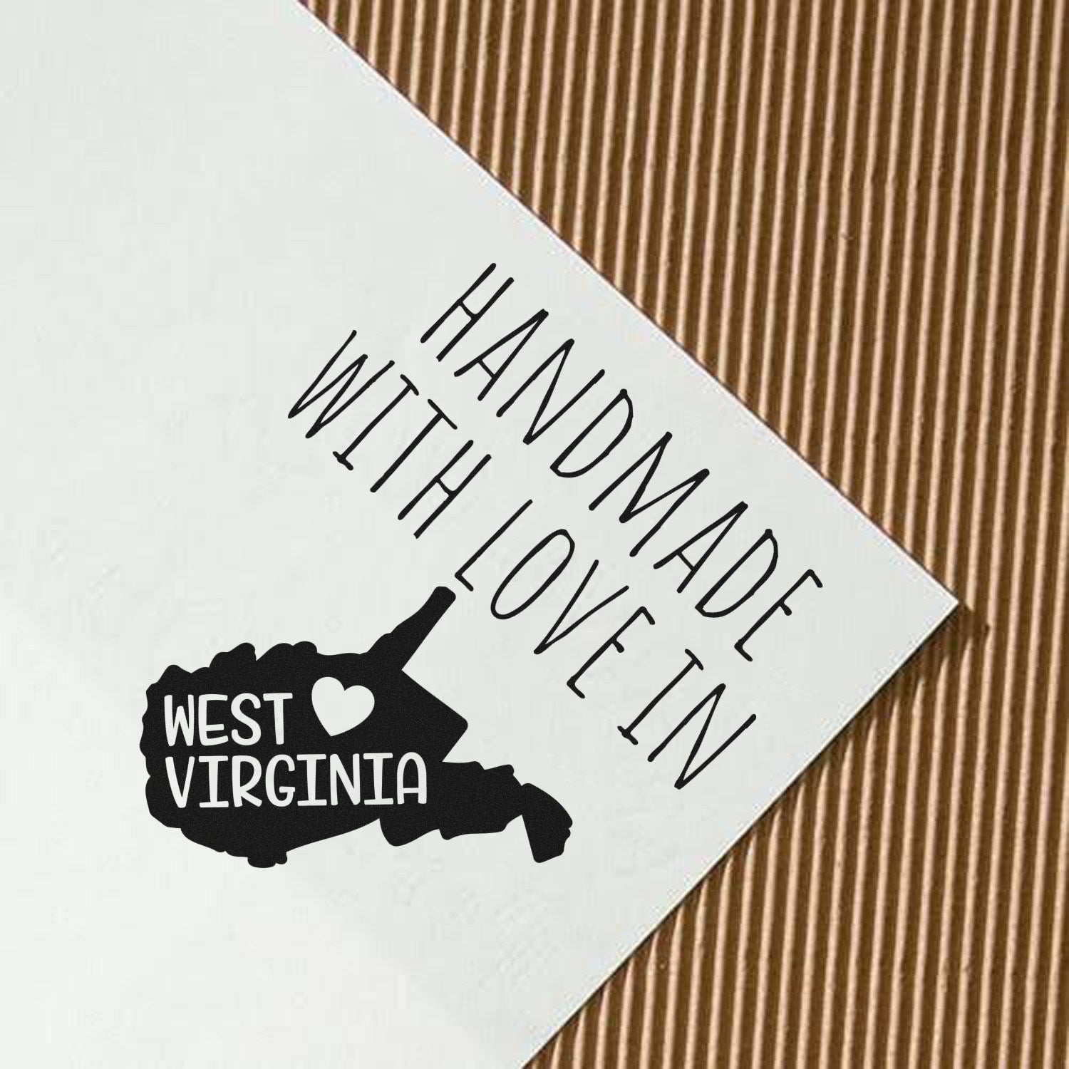 Self-Inking West Virginia Handmade with Love Stamp on paper, featuring a black silhouette of West Virginia with a heart, perfect for crafts and gifts.