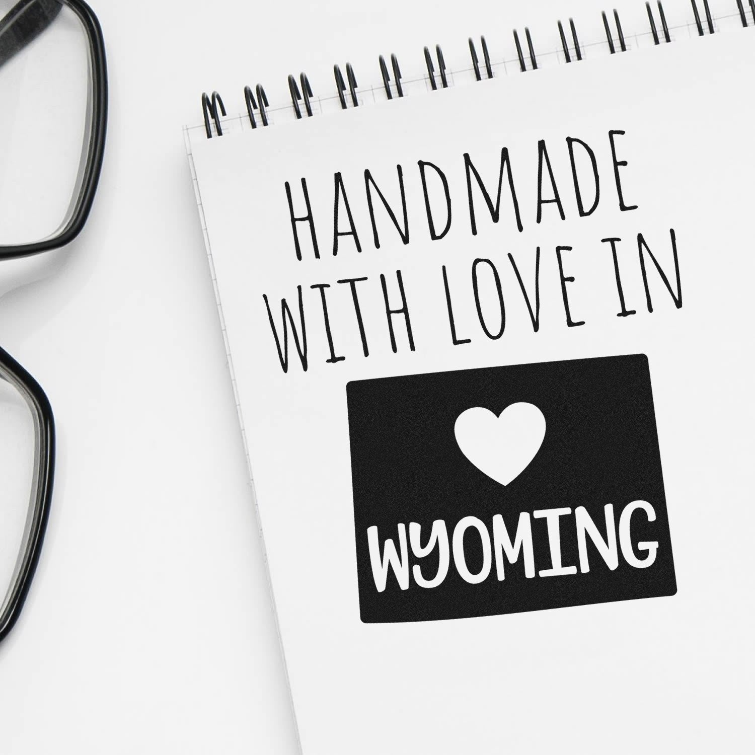 Self-Inking Wyoming Handmade with Love Stamp on notepad, featuring a heart and 'WYOMING' text, perfect for crafts and gifts. Black ink, easy to use, and durable design.