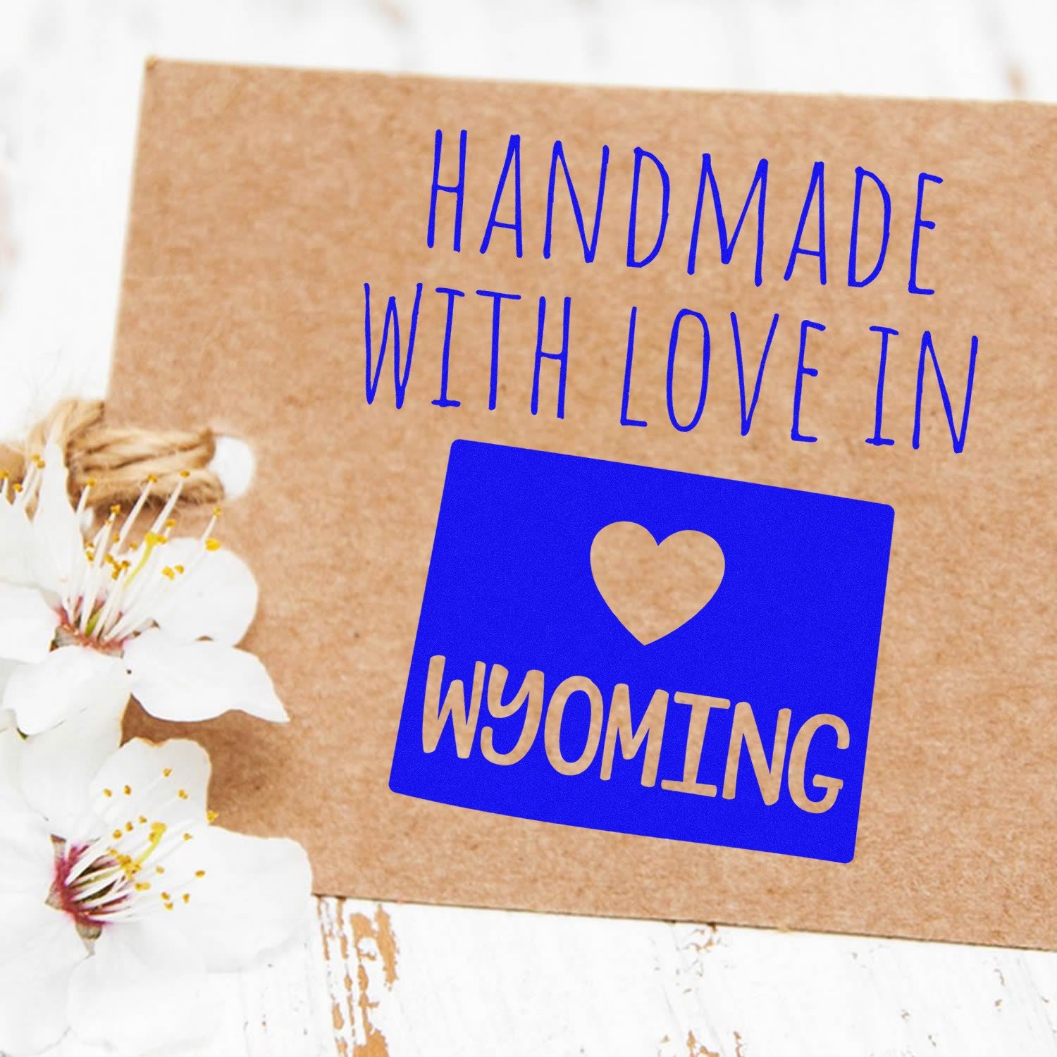 Handmade with Love in Wyoming Slim Pre-Inked Stamp on a brown card with white flowers, featuring blue text and a heart design. Perfect for adding a personal touch to crafts and gifts.