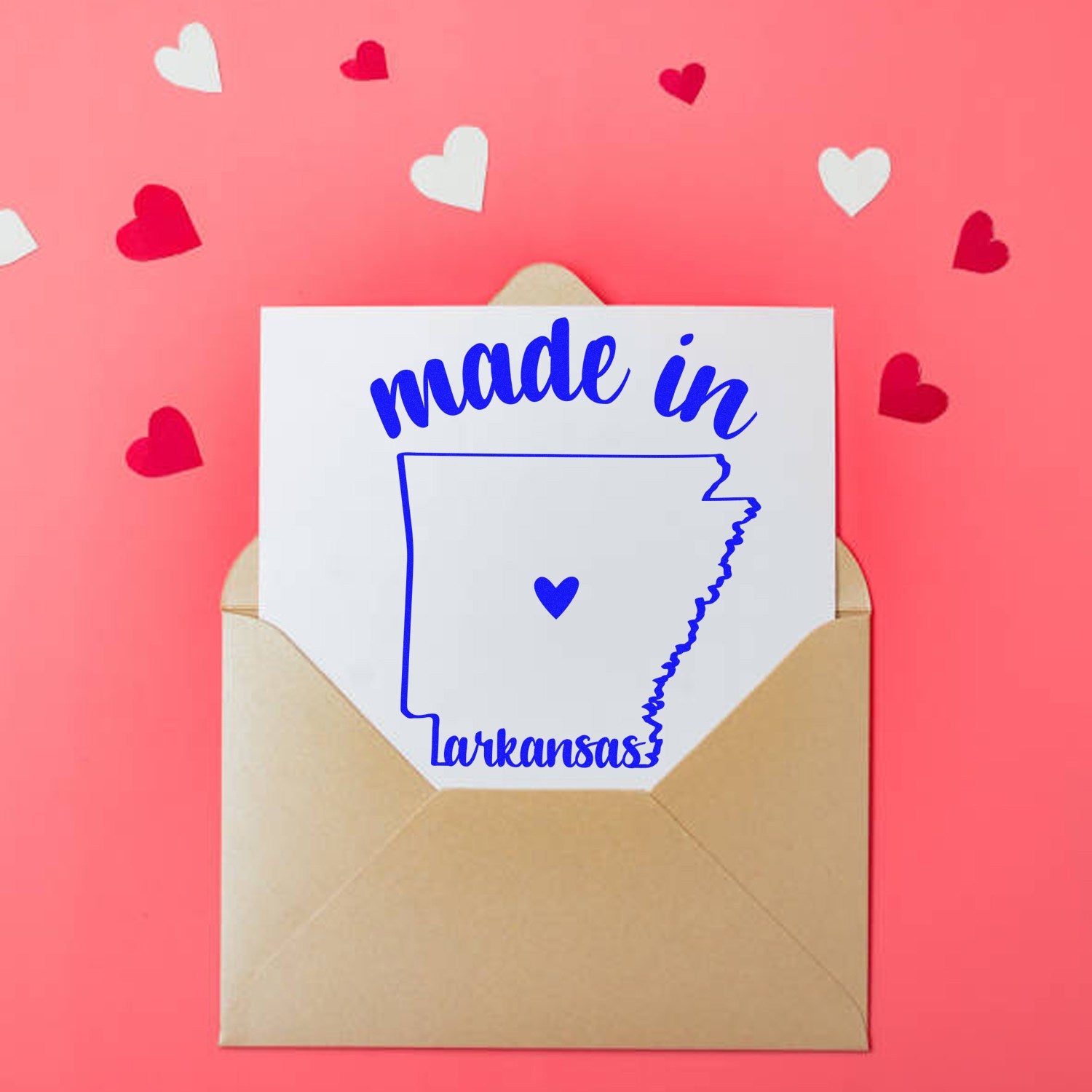 Slim Pre-Inked Stamp Arkansas Made in Stamp on a pink background with red and white hearts, featuring a blue outline of Arkansas and made in Arkansas text. Perfect for crafts and gifts.