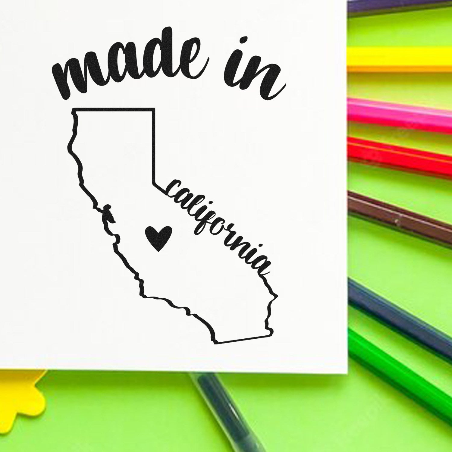 Image of a Slim Pre-Inked Stamp California Made in Stamp, featuring a black outline of California with made in and California text, and a heart symbol, on a colorful background.