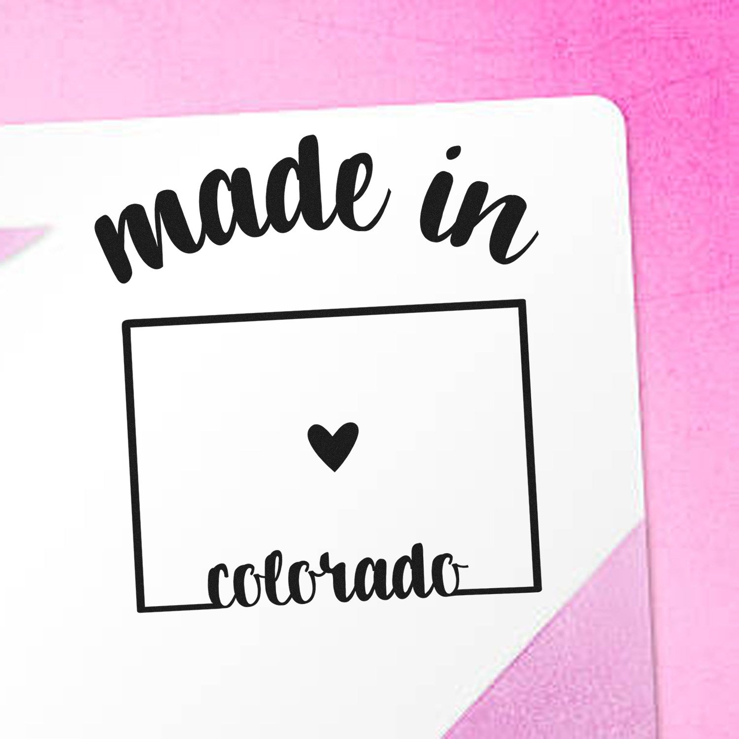 Made in Colorado Stamp Pre-Inked on white paper with a pink background, featuring a heart inside a rectangle, perfect for adding a personal touch to your crafts and stationery.