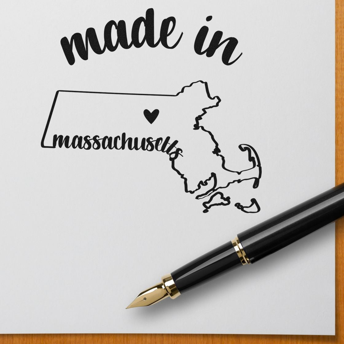 Self-Inking Handmade with Love in Massachusetts Stamp featuring a map outline with heart, shown on white paper with a black pen. Perfect for crafts and gifts.