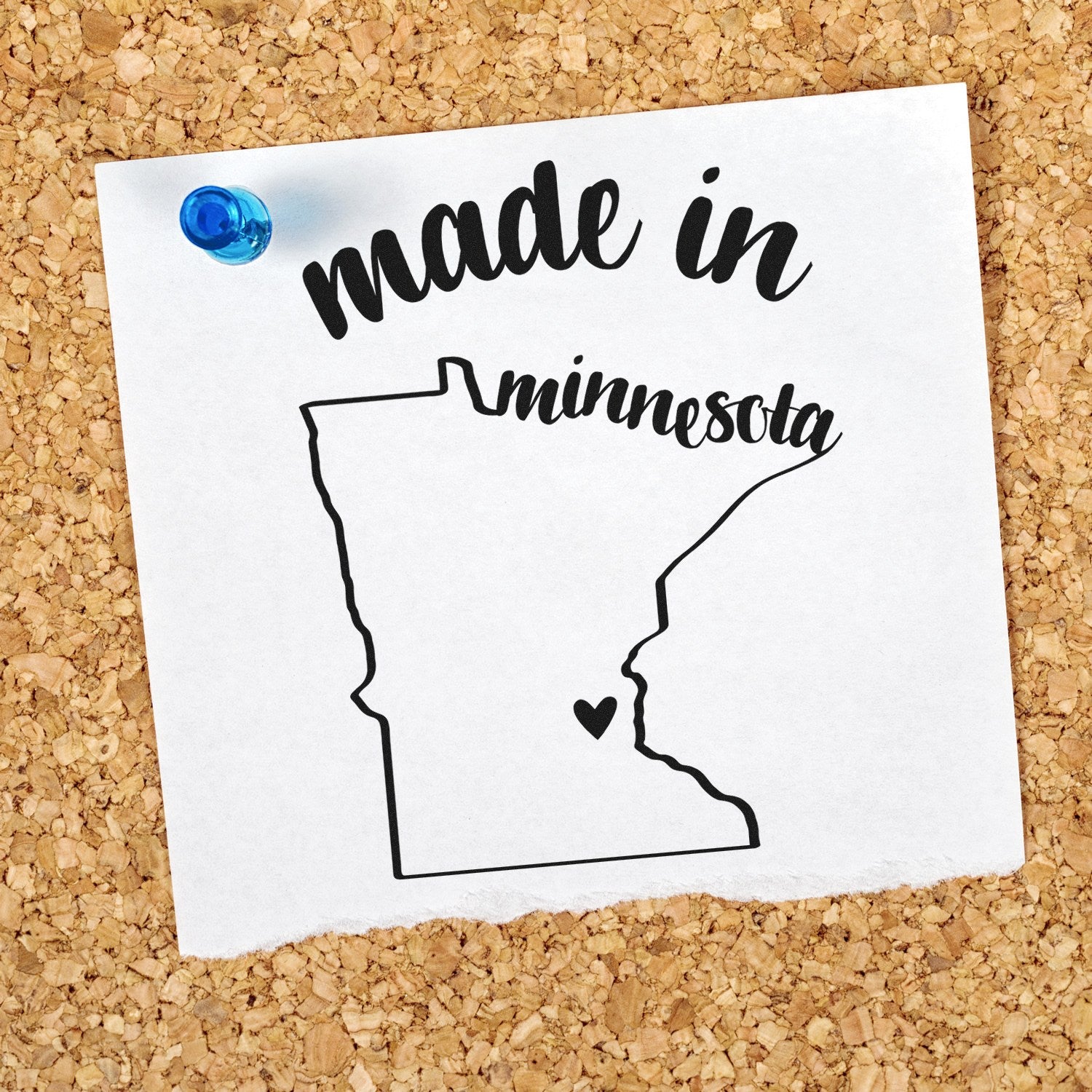 Self-Inking Handmade with Love in Minnesota Stamp on corkboard, featuring a map outline with a heart, pinned with a blue pushpin. Perfect for crafts and personalized projects.