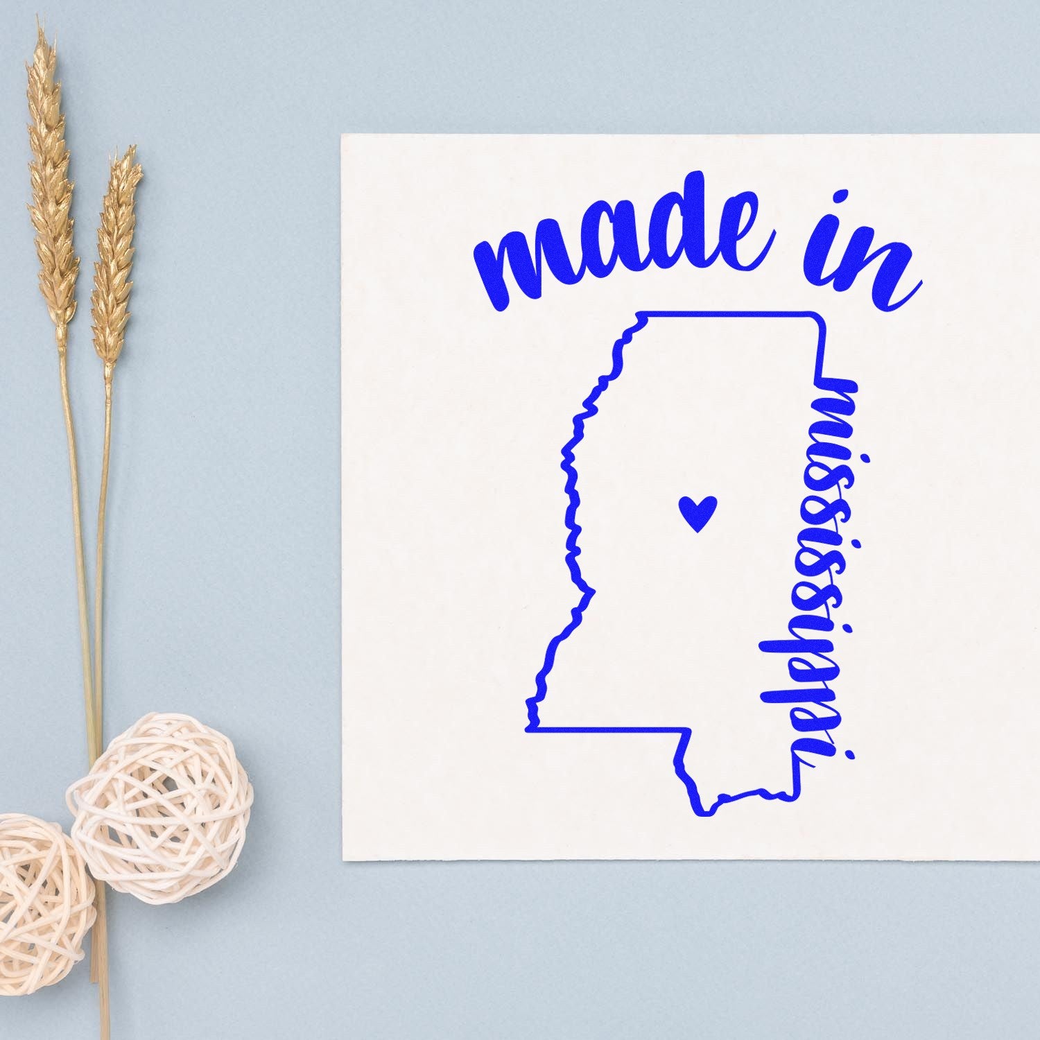 Self-Inking Handmade with Love in Mississippi Stamp featuring a blue outline of Mississippi with a heart, 'made in mississippi' text, on a light background with decorative elements.