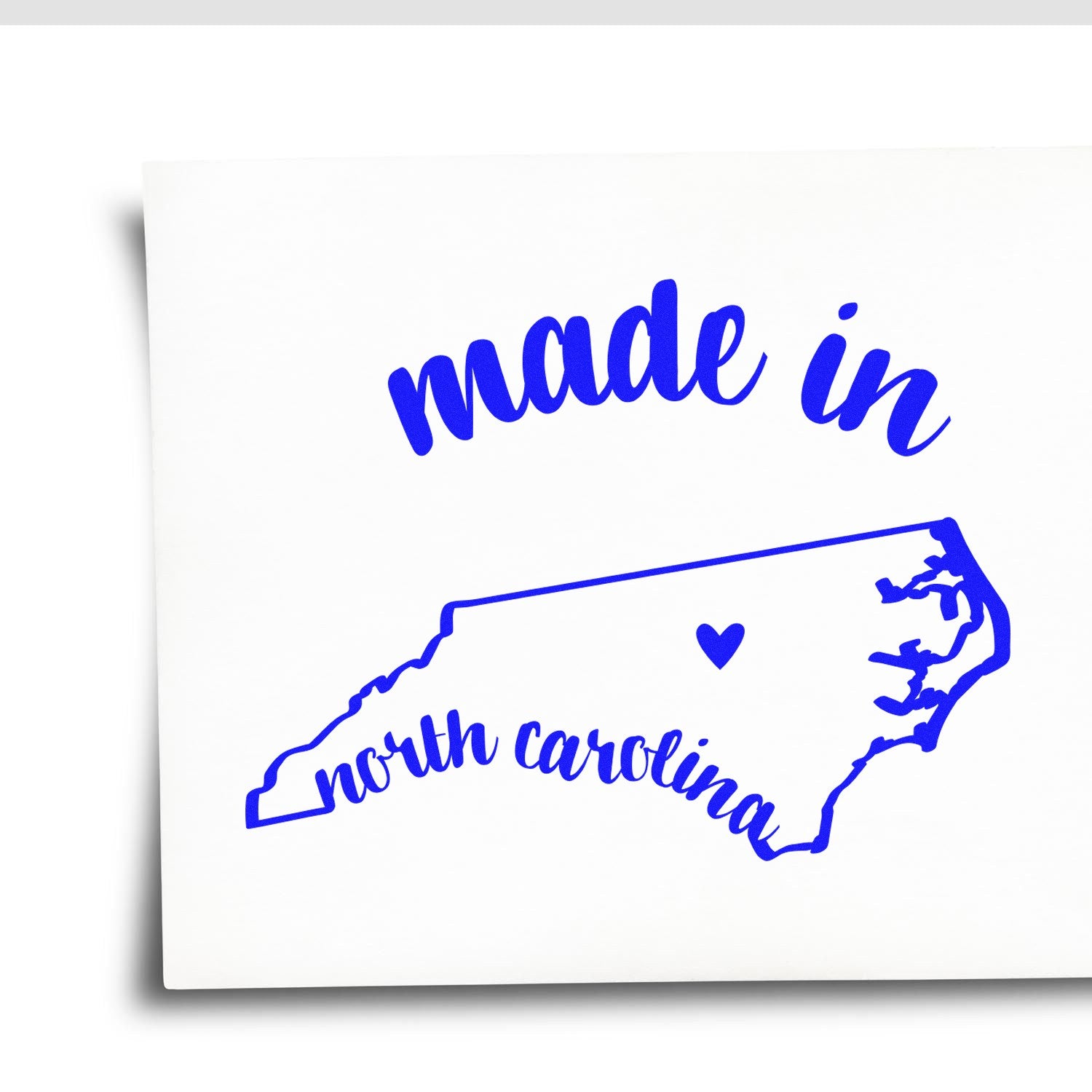 Made with Love in North Carolina Rubber Stamp featuring a blue outline of North Carolina with a heart, and the words 'made in' above and 'north carolina' below on a white background.