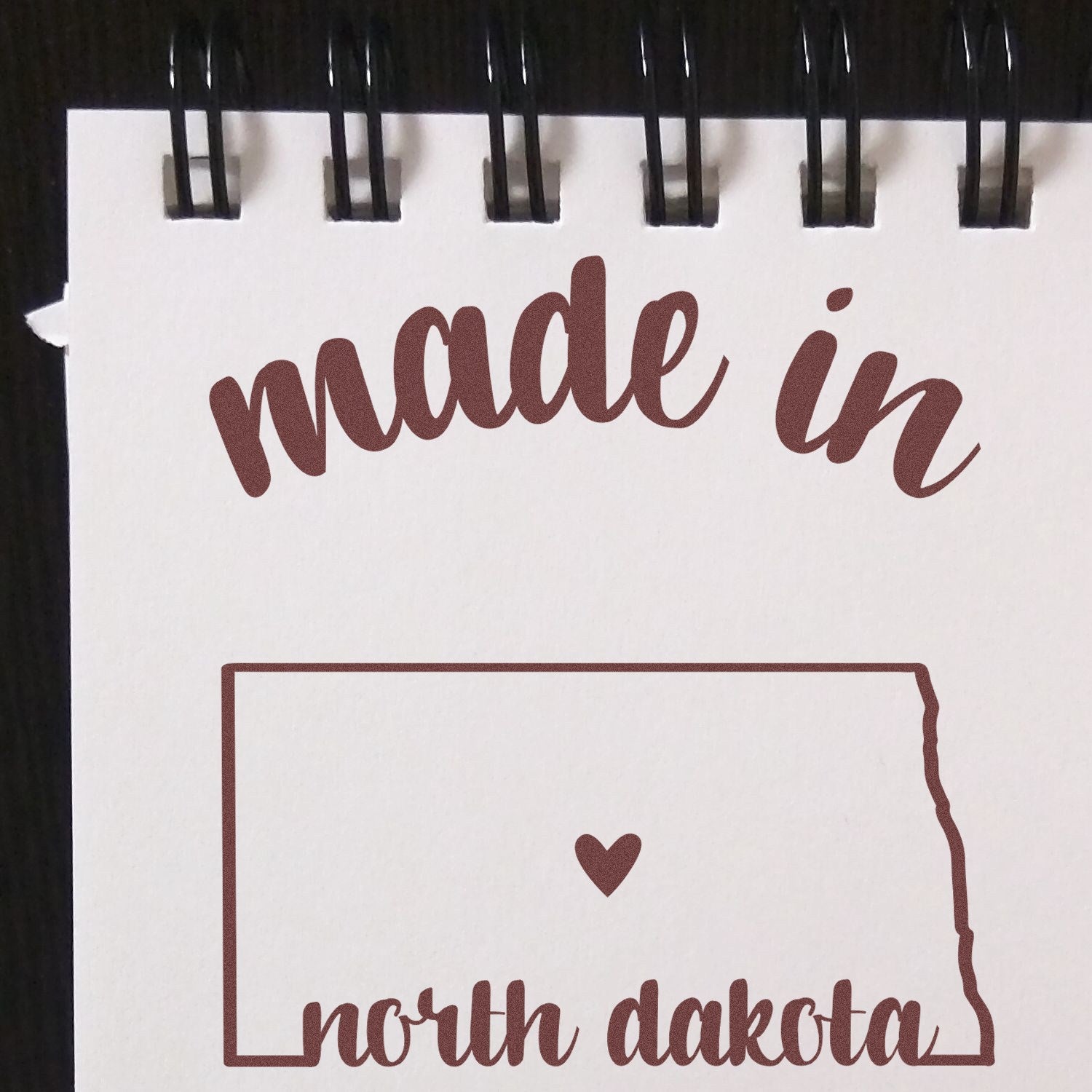 Self-Inking Handmade with Love in North Dakota Stamp on notepad, featuring a heart within the state outline, perfect for crafts and gifts.