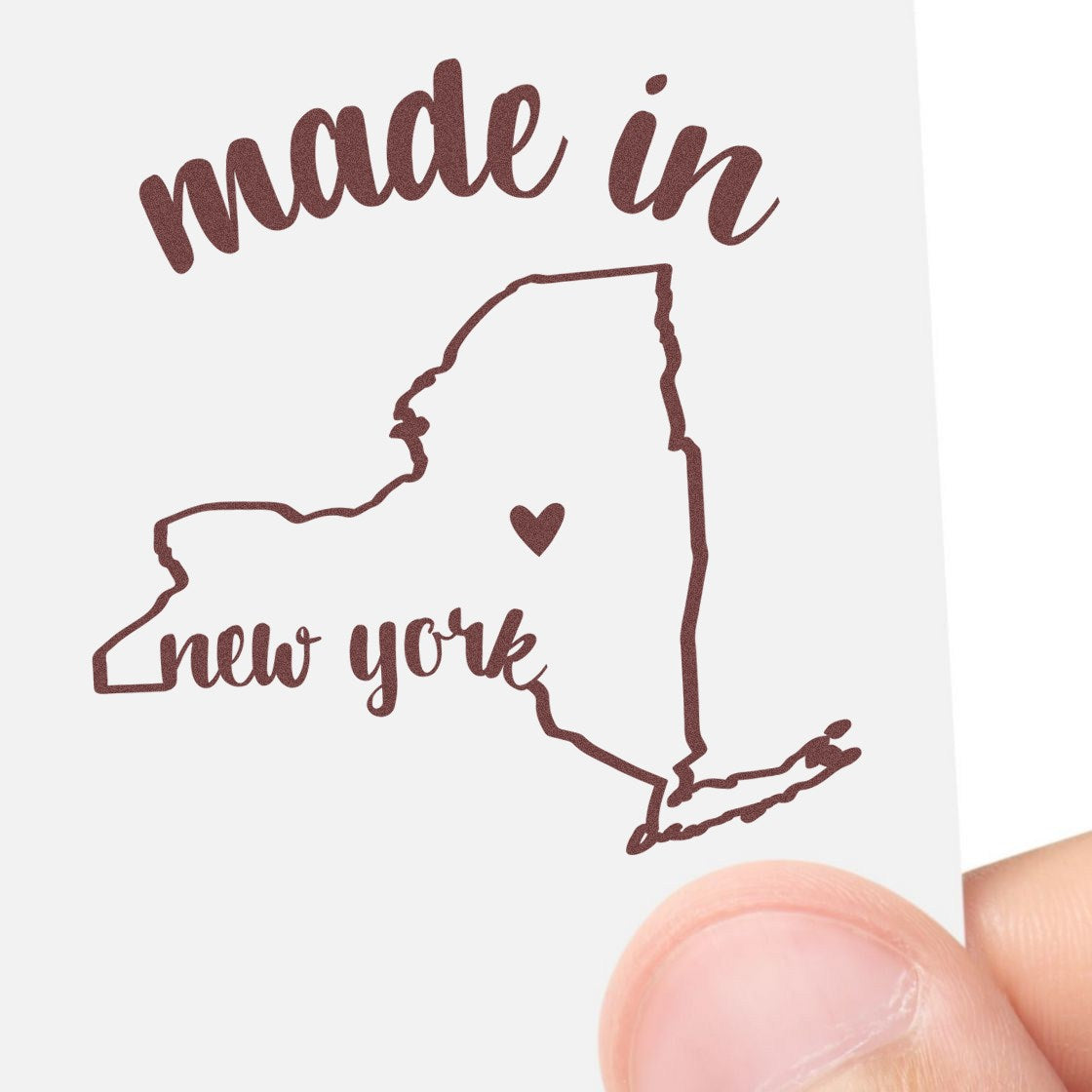 Made with Love in New York Rubber Stamp featuring a heart inside a New York state outline, held by a hand. Perfect for crafts and personalized projects.