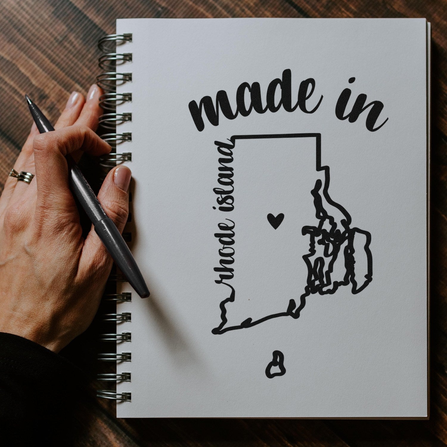 Self-Inking Handmade with Love in Rhode Island Stamp on a notebook, featuring a map outline and heart design, perfect for adding a personal touch to crafts and gifts.