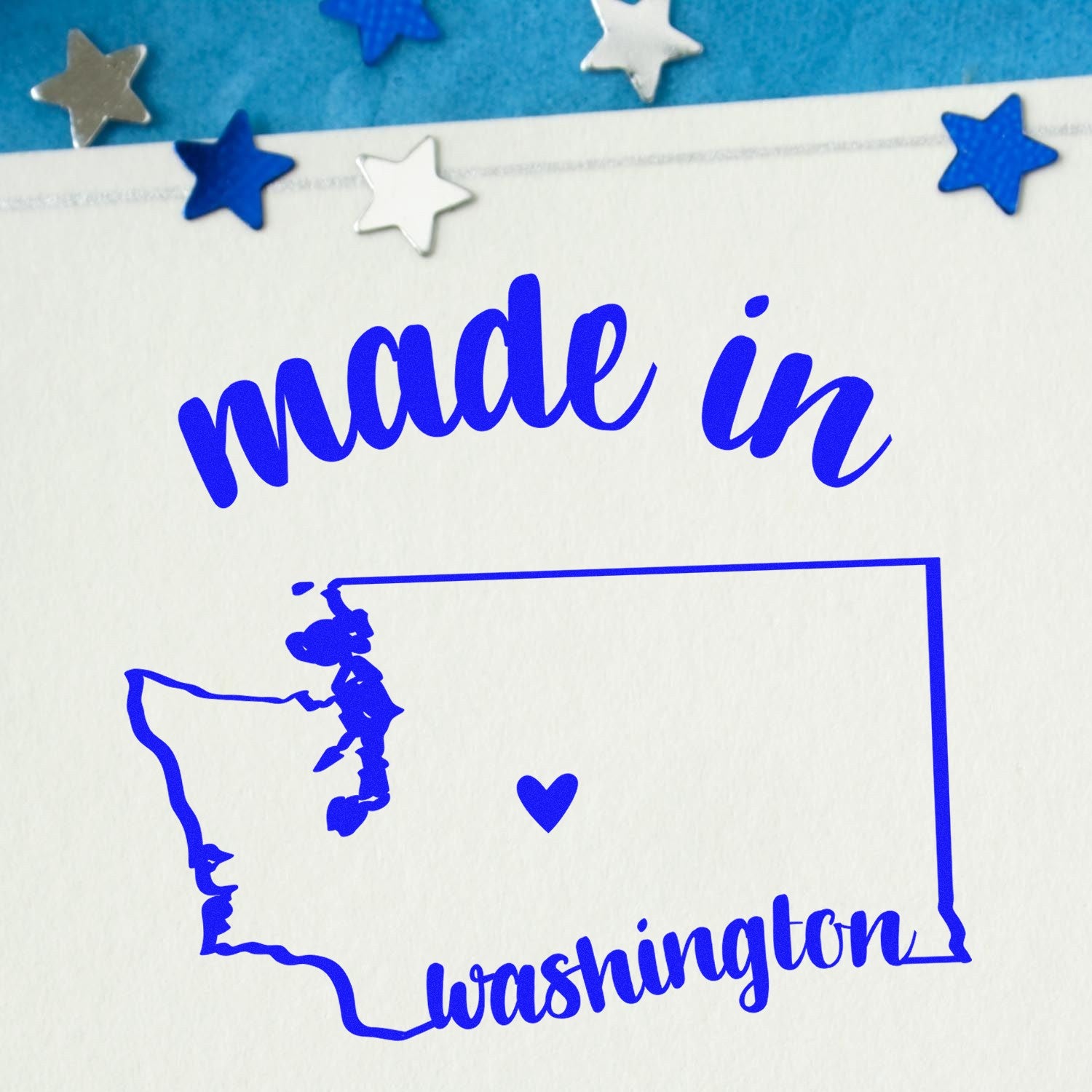 Made with Love in Washington Rubber Stamp featuring a blue outline of Washington state with a heart, surrounded by blue and silver stars on a white background.