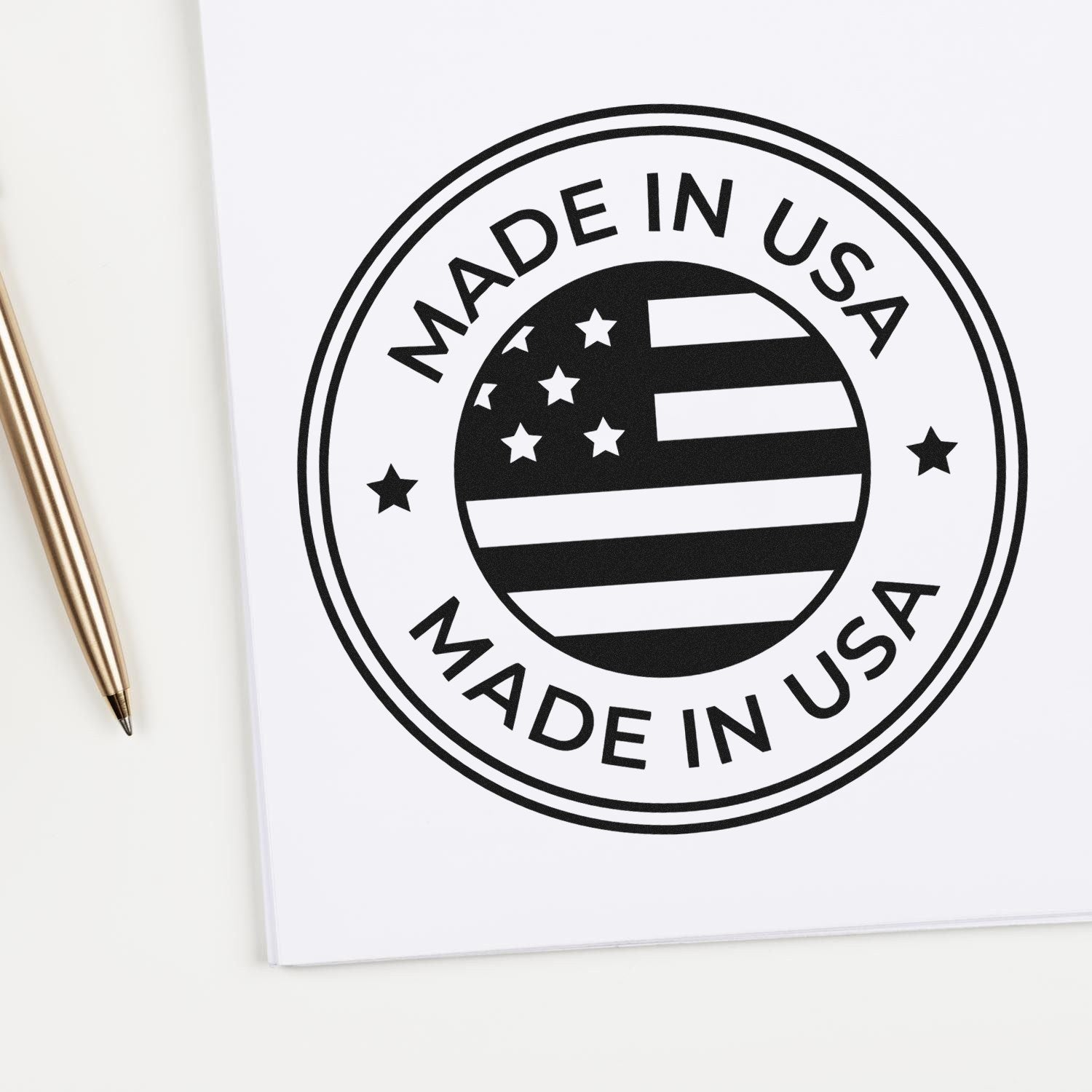 Slim Pre-Inked Patriotic Seal Stamp featuring a Made in USA design with stars and stripes, shown on white paper next to a gold pen. Perfect for adding a patriotic touch to documents.