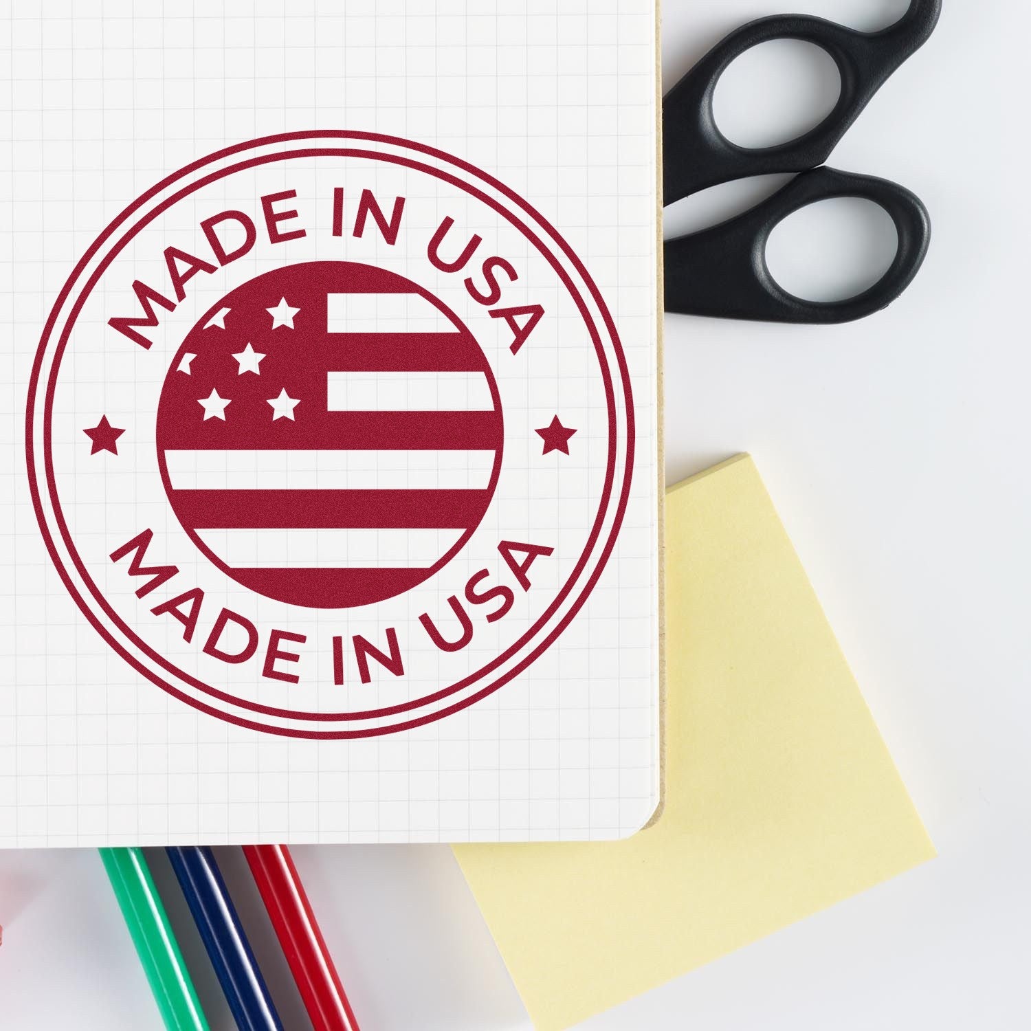 Slim Pre-Inked Patriotic Seal Stamp featuring a Made in USA design with stars and stripes, shown on paper with colorful pens and scissors nearby.