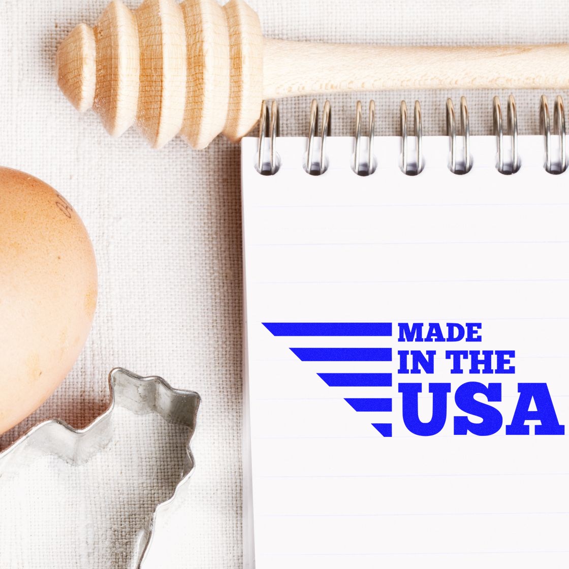 PSI Pre-Inked Patriotic and Proud Stamp displaying Made in the USA in blue on a notepad, surrounded by a honey dipper, egg, and USA-shaped cookie cutter.