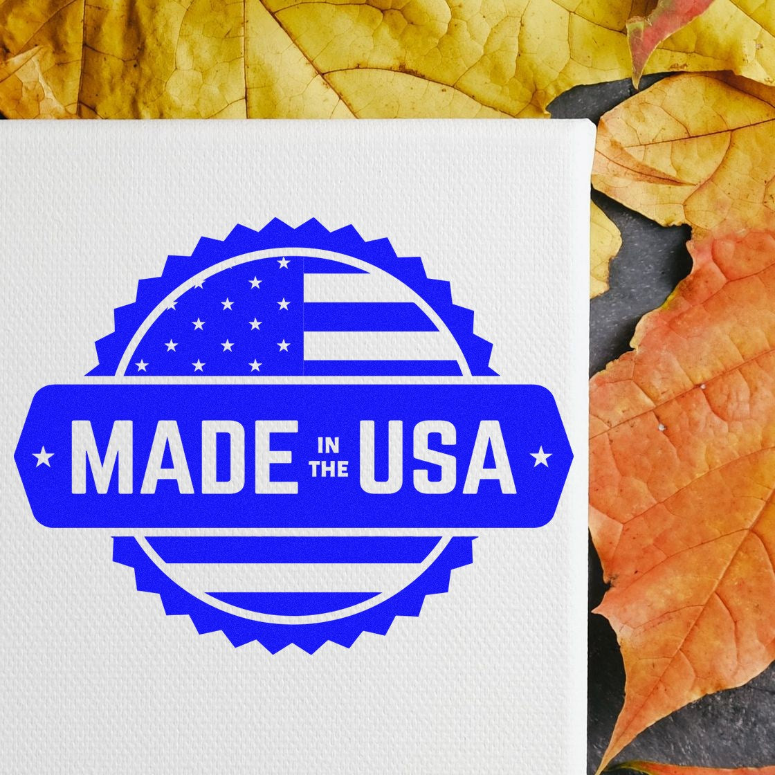 PSI Pre-Inked American Craftsmanship Seal Stamp with 'Made in the USA' design in blue, displayed on a canvas with autumn leaves background.