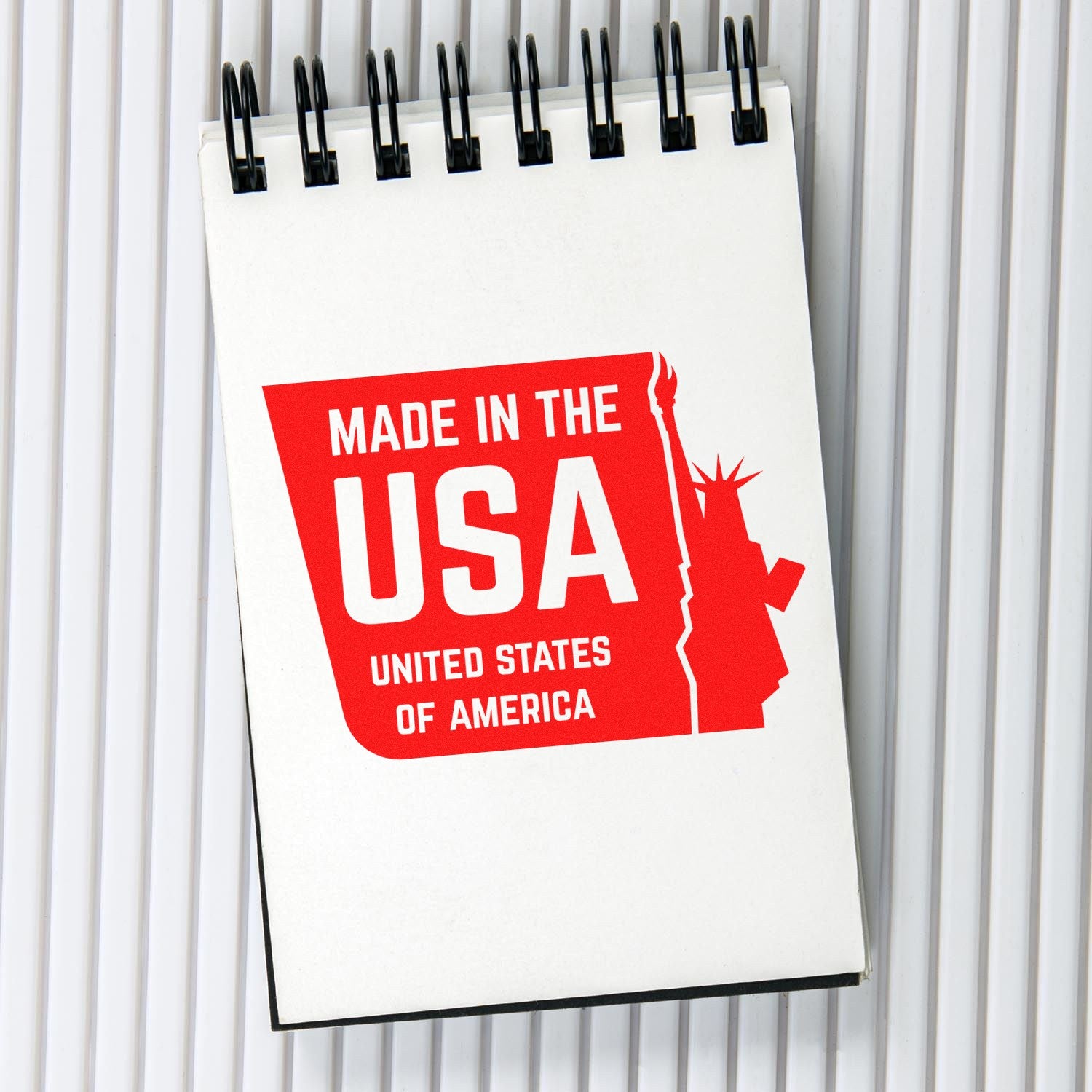 Image of a PSI Pre-Inked Liberty Made USA Stamp imprint on a notepad, featuring a red design with the Statue of Liberty silhouette and Made in the USA text.