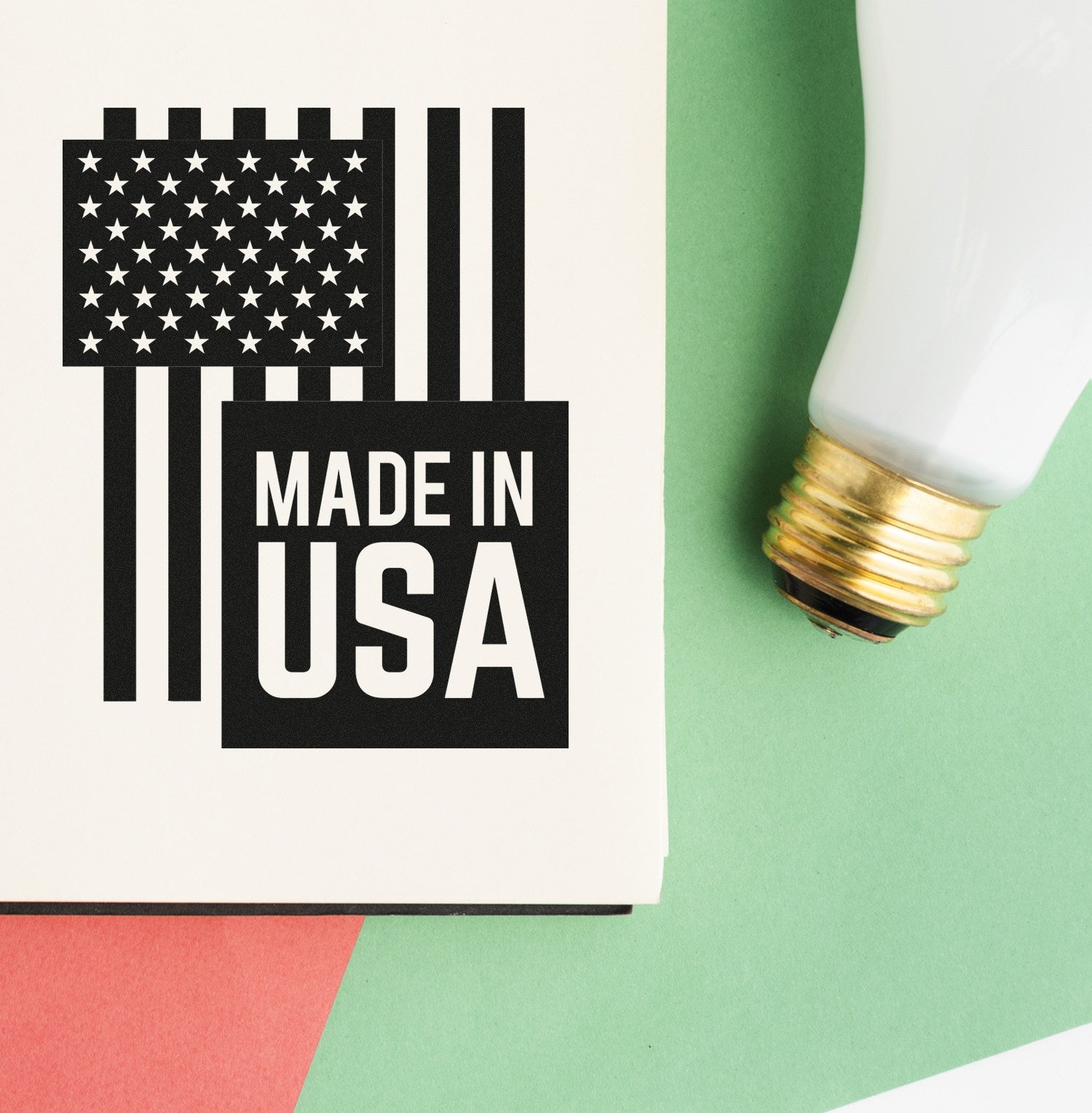 Slim Pre-Inked USA Patriotic Pride Stamp featuring a black and white American flag design with Made in USA text, shown on a colorful background next to a light bulb.