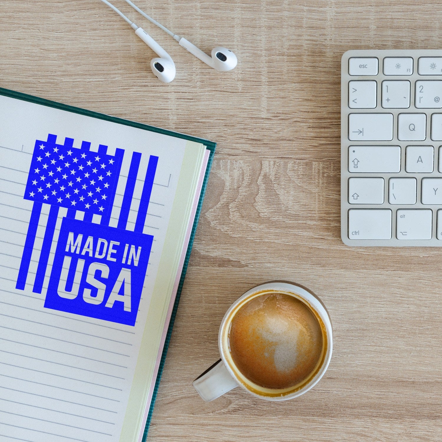 PSI Pre-Inked USA Patriotic Pride Stamp imprint on notebook, featuring American flag design and 'Made in USA' text, next to a coffee cup, keyboard, and earphones on a wooden desk.