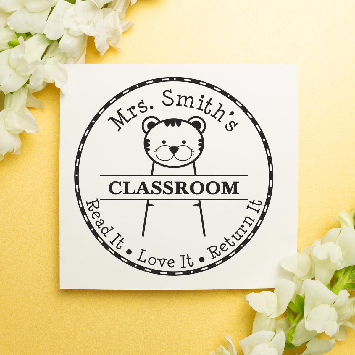 Black custom classroom stamp seal with tiger mascot on a white card, set against a yellow floral background, Mrs. Smith's classroom.