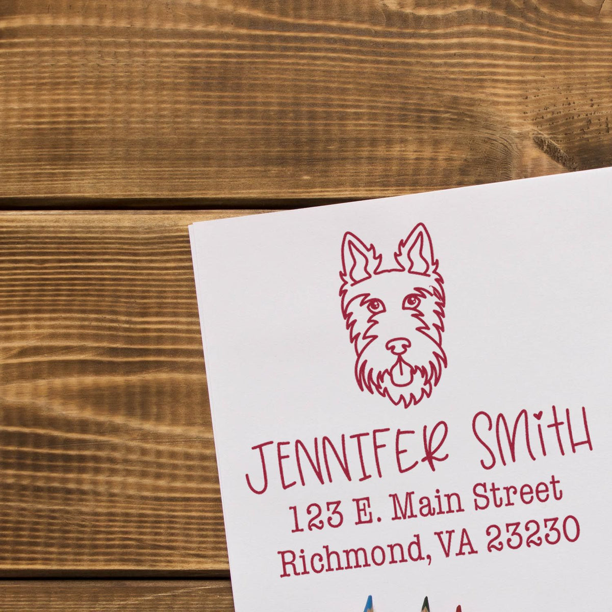Custom red business stamp and seal on white card, featuring a dog logo, name, and address on rustic wood.