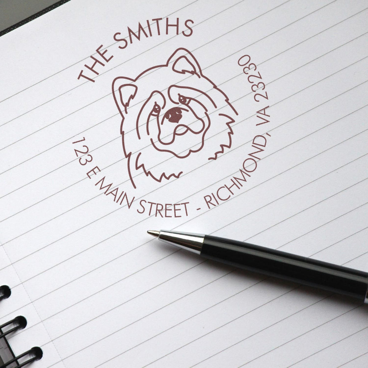 Maroon bulldog custom stamp seal on lined notebook, with The Smiths address and black pen.
