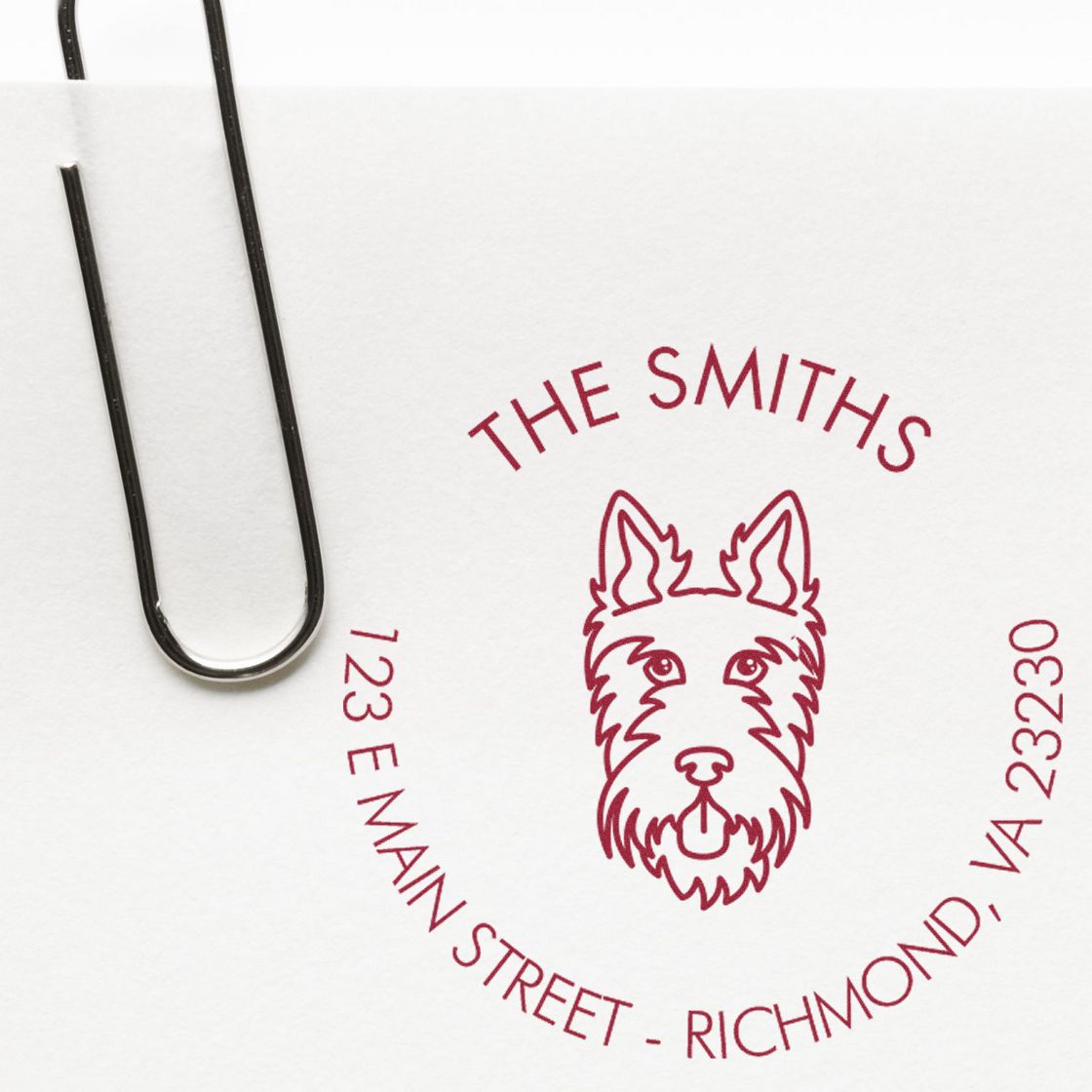 Burgundy custom stamp seal with dog logo and THE SMITHS return address on white paper, beside a black paperclip.