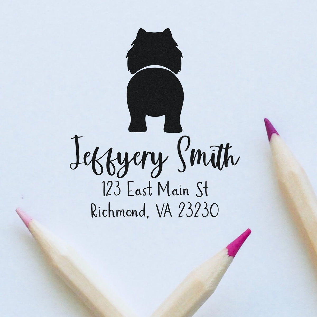 Black custom stamp and seal with dog silhouette, Jeffrey Smith address in script on white paper, framed by pink-tipped pencils.