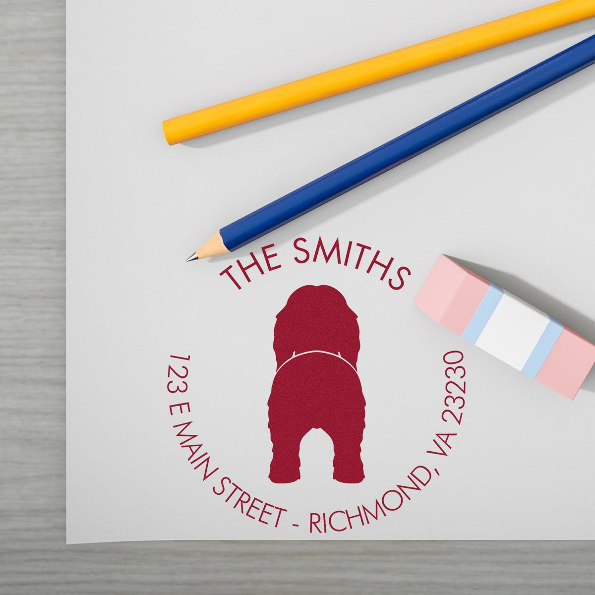 Custom red stamp seal for The Smiths on white paper, with blue and yellow pencils and a pink eraser.