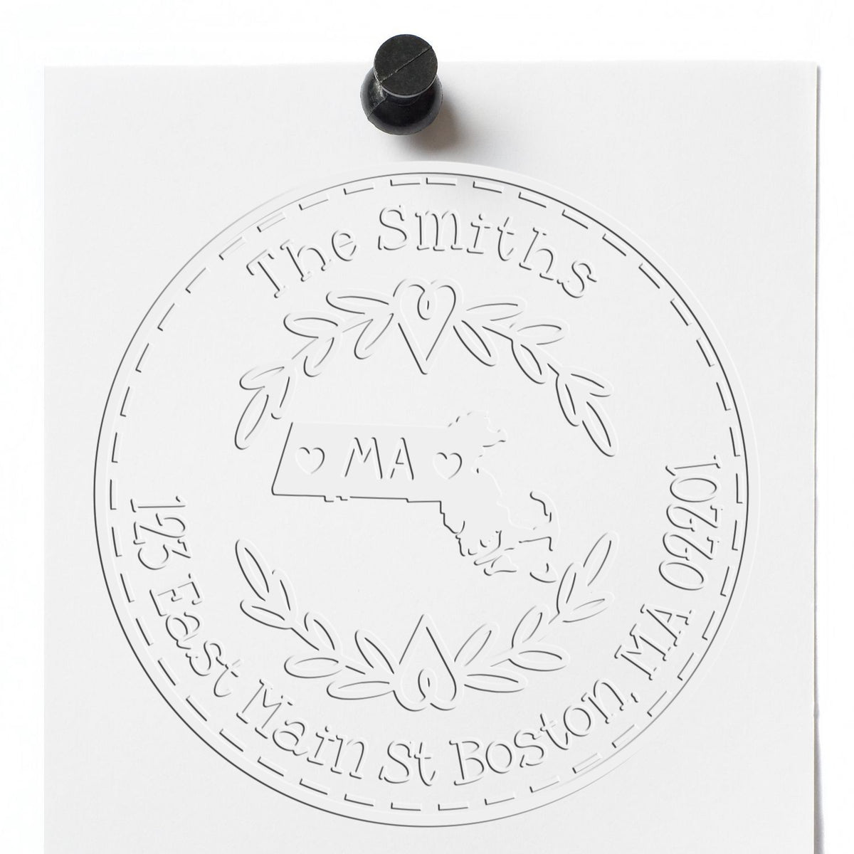 Black stamp handle on white paper with embossed circular custom seal for The Smiths, featuring MA map and laurel wreath.
