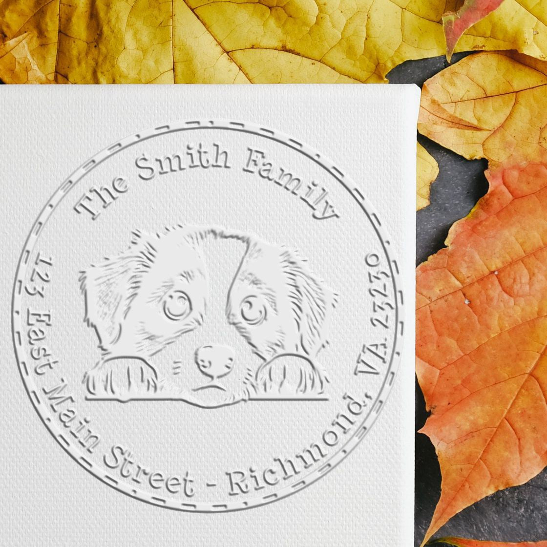 Custom embossed seal stamp with a puppy illustration on white cardstock, set against yellow and orange autumn leaves.